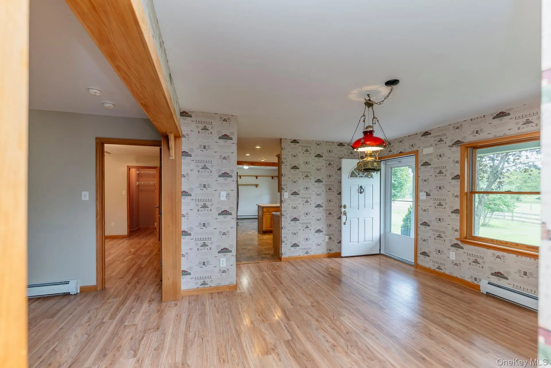Foyer entrance featuring a baseboard radiator, wallpapered walls, baseboards, and light wood-type flooring Foyer entrance featuring a baseboard radiator, wallpapered walls, baseboards, and light wood-type flooring