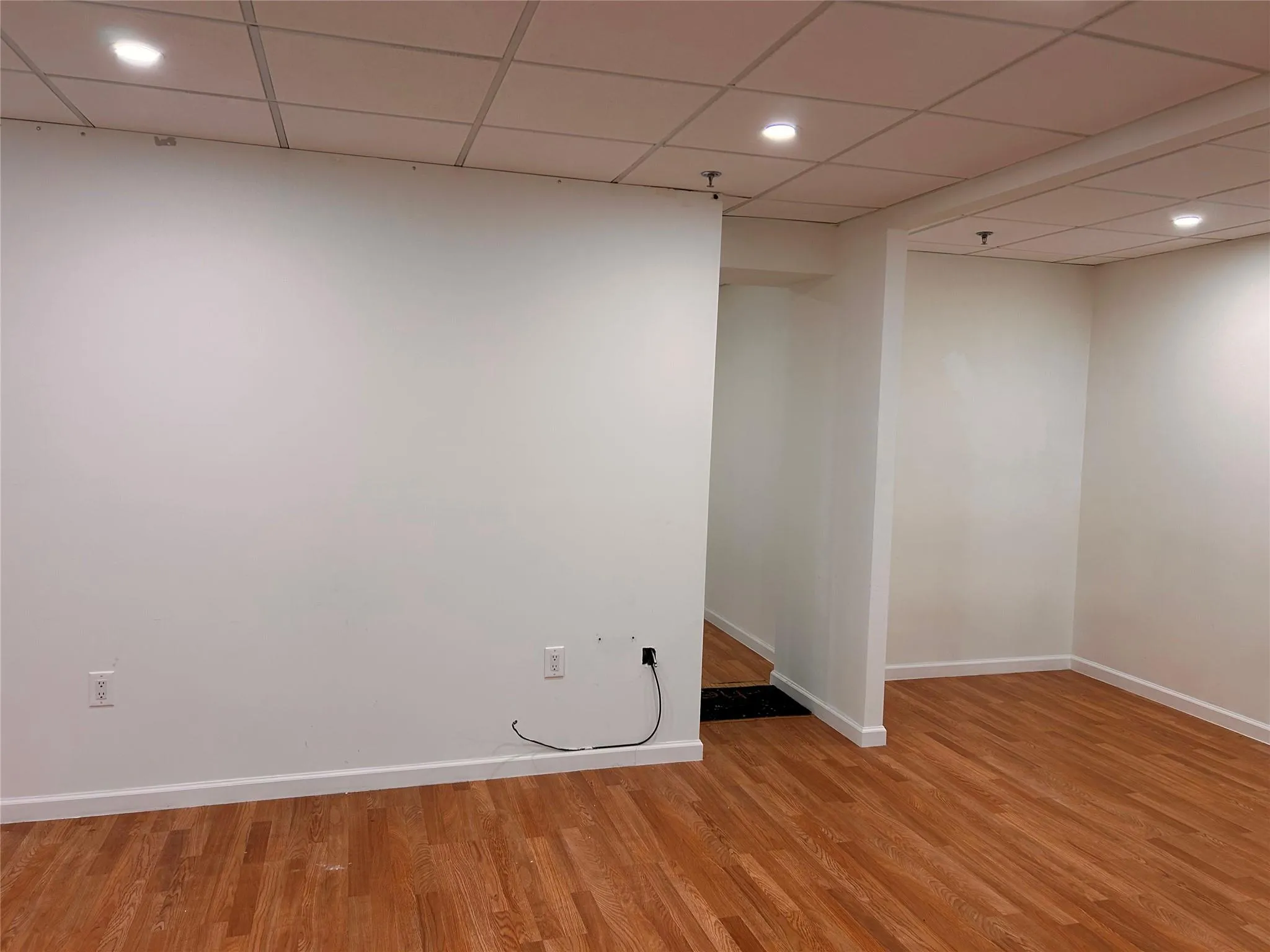 Finished basement featuring light wood-type flooring, baseboards, recessed lighting, and a paneled ceiling Finished basement featuring light wood-type flooring, baseboards, recessed lighting, and a paneled ceiling