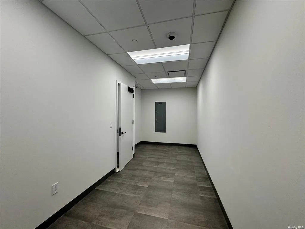 Empty room with a paneled ceiling, electric panel, and baseboards Empty room with a paneled ceiling, electric panel, and baseboards