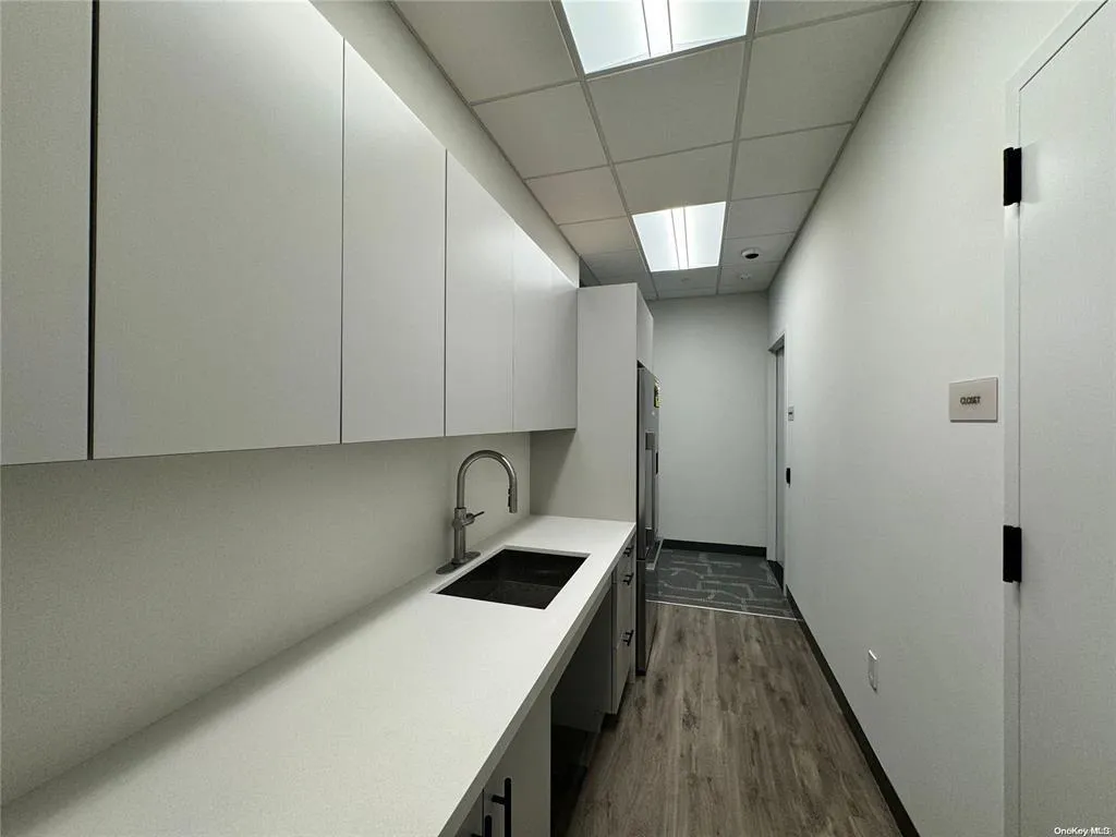 Laundry area featuring a sink, dark wood finished floors, and baseboards Laundry area featuring a sink, dark wood finished floors, and baseboards