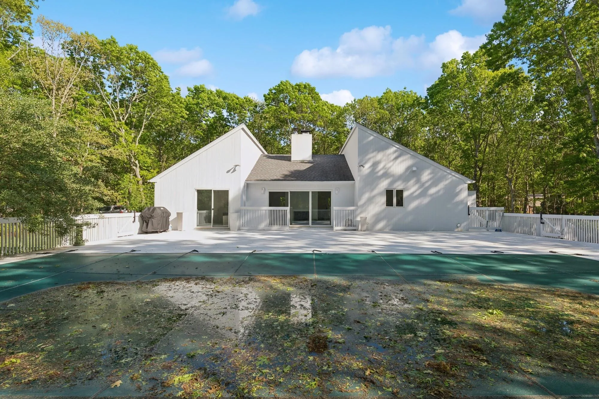 Rear view of house with a patio, a chimney, and a gate Rear view of house with a patio, a chimney, and a gate