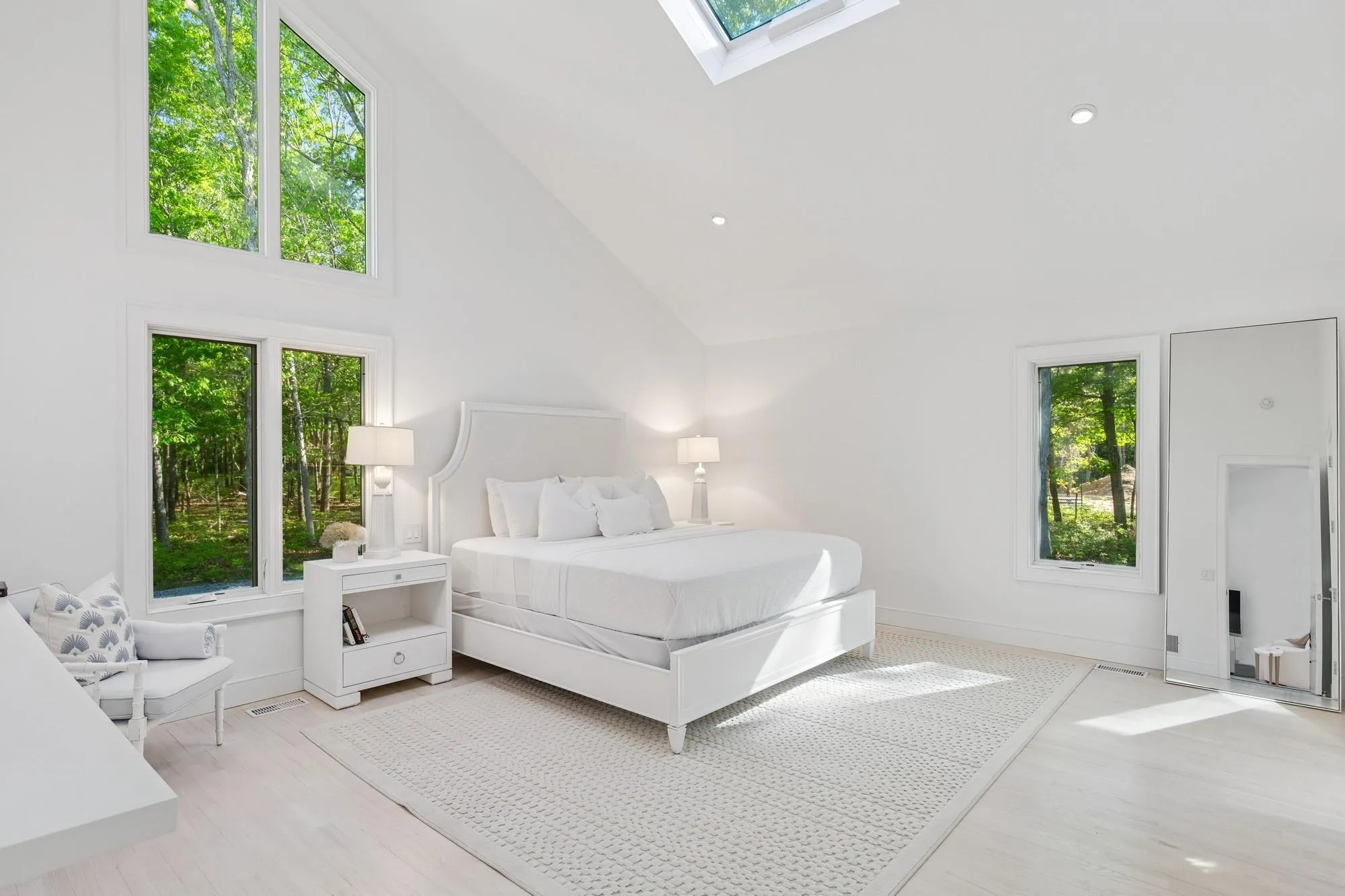 Bedroom with multiple windows, wood finished floors, high vaulted ceiling, and a skylight Bedroom with multiple windows, wood finished floors, high vaulted ceiling, and a skylight