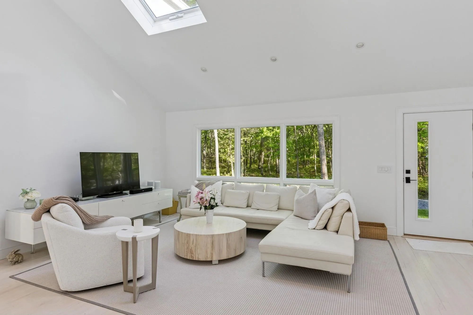 Living room with light wood-type flooring, high vaulted ceiling, and a skylight Living room with light wood-type flooring, high vaulted ceiling, and a skylight