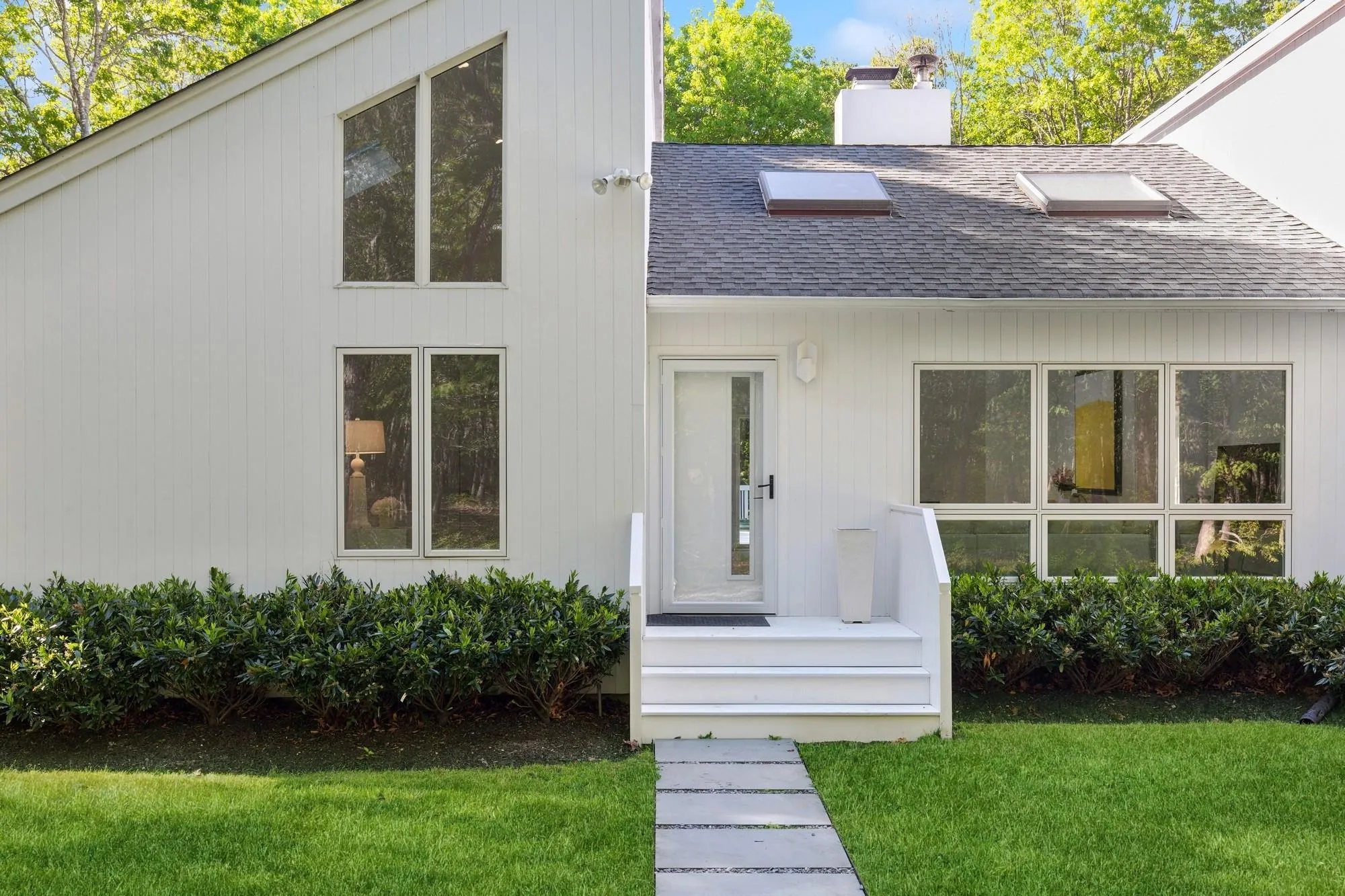 Mid-century home featuring roof with shingles, a front lawn, and a chimney Mid-century home featuring roof with shingles, a front lawn, and a chimney
