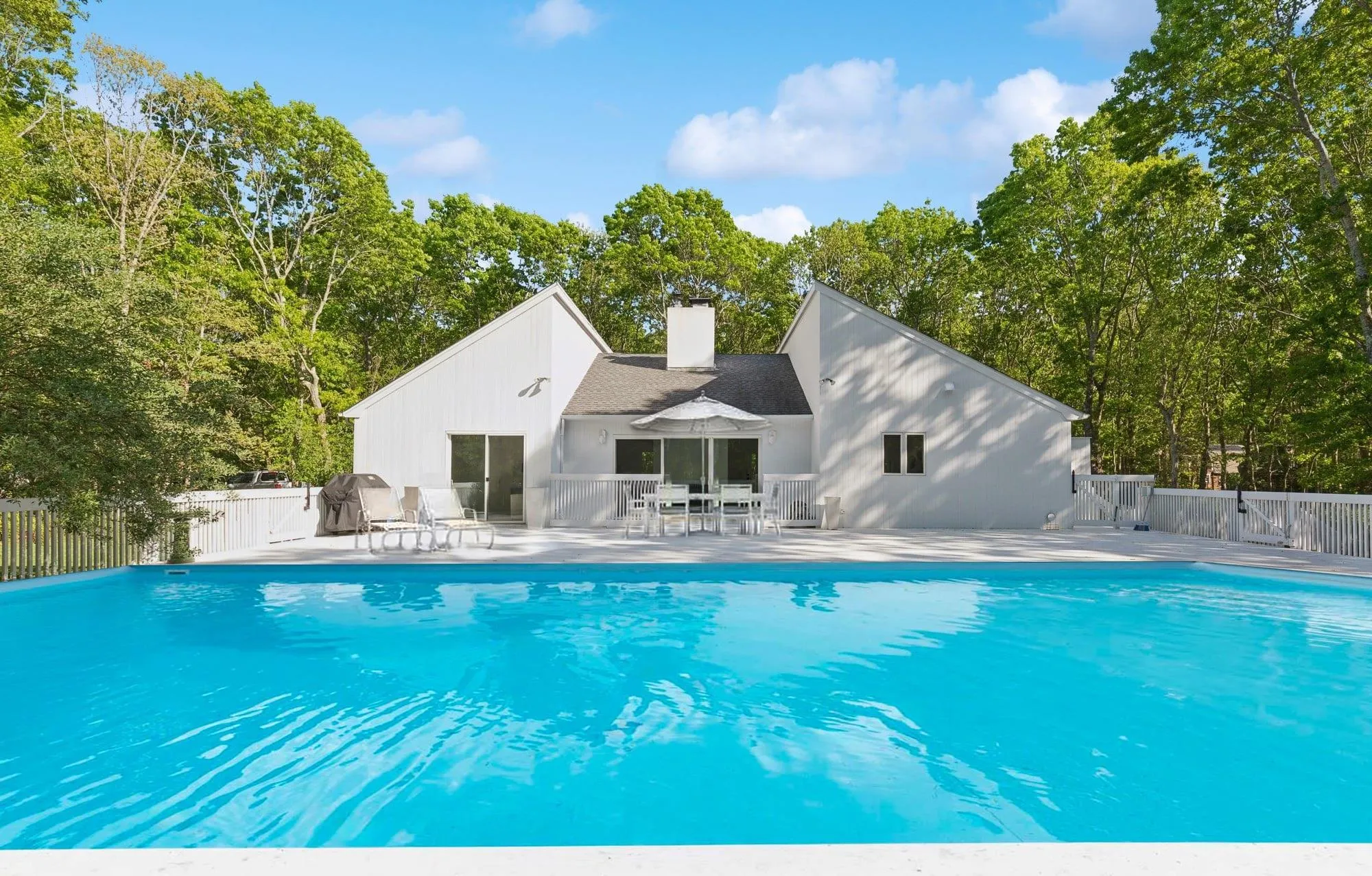 View of pool featuring a patio and view of scattered trees View of pool featuring a patio and view of scattered trees