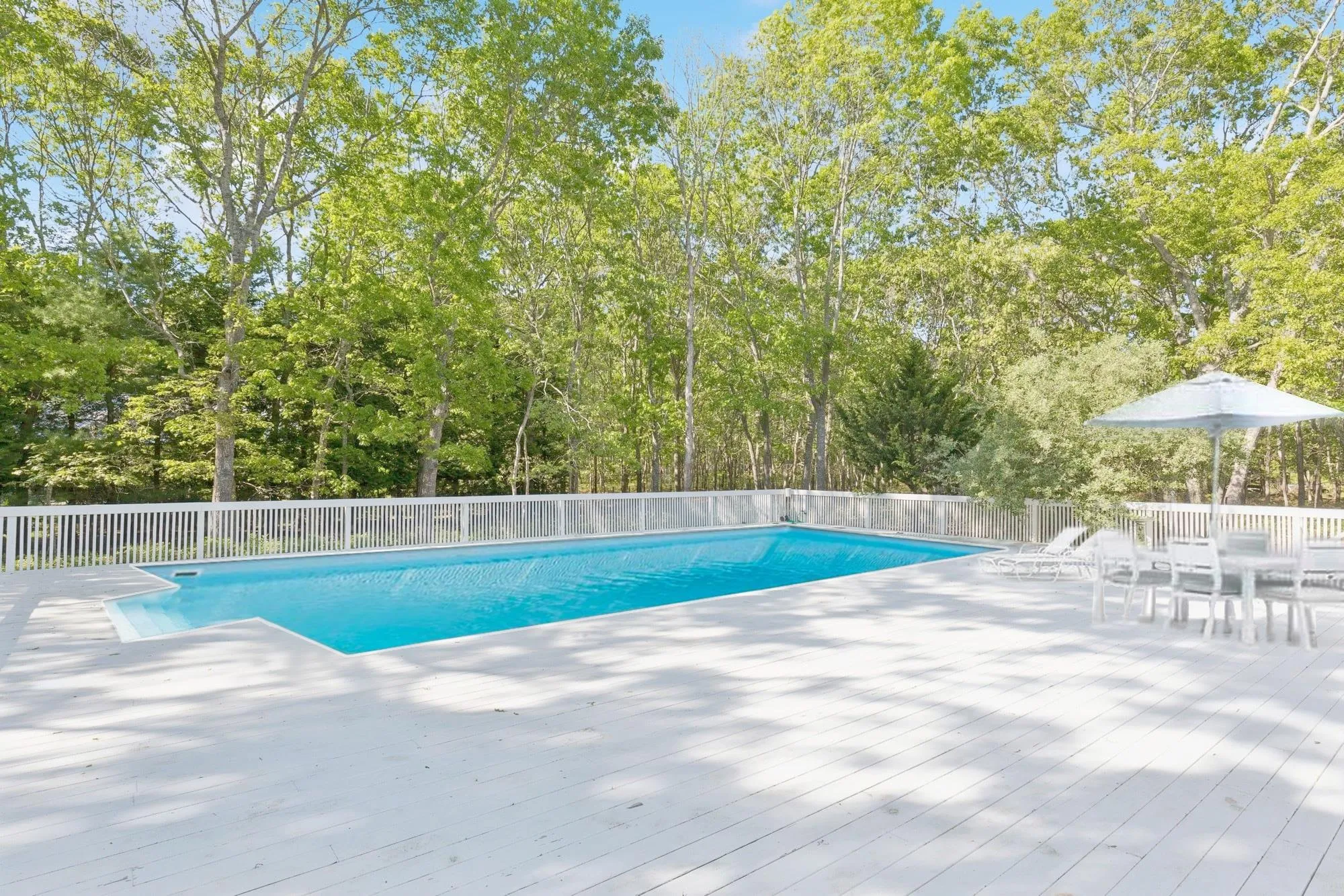View of pool featuring view of scattered trees, a patio, and a deck View of pool featuring view of scattered trees, a patio, and a deck