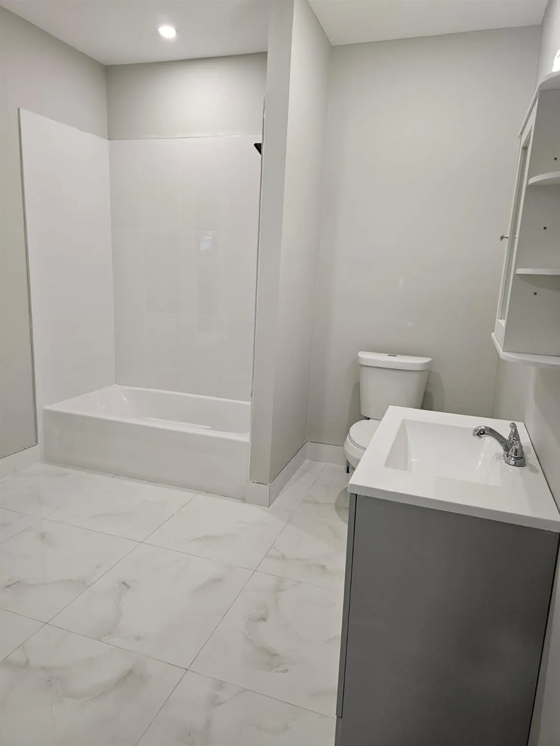 Bathroom with marble look tiles, toilet, baseboards, vanity, and recessed lighting Bathroom with marble look tiles, toilet, baseboards, vanity, and recessed lighting