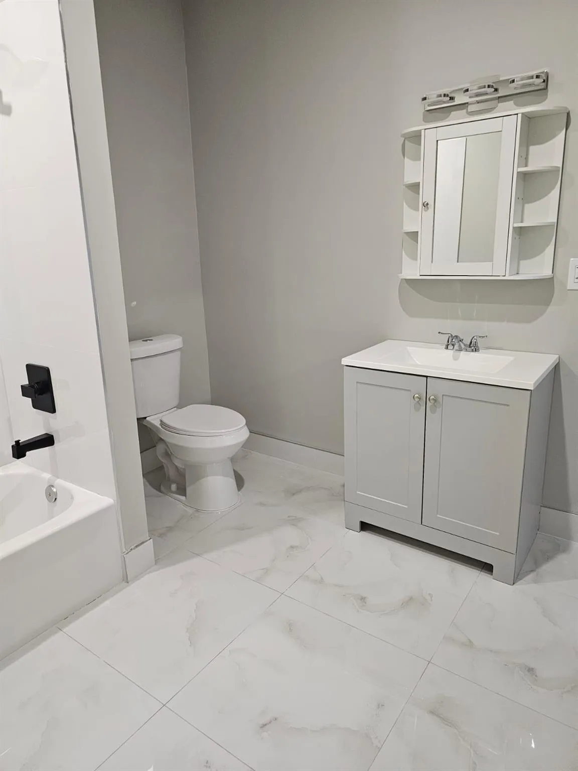 Full bath featuring marble look tile flooring, toilet, baseboards, vanity, and shower / washtub combination Full bath featuring marble look tile flooring, toilet, baseboards, vanity, and shower / washtub combination