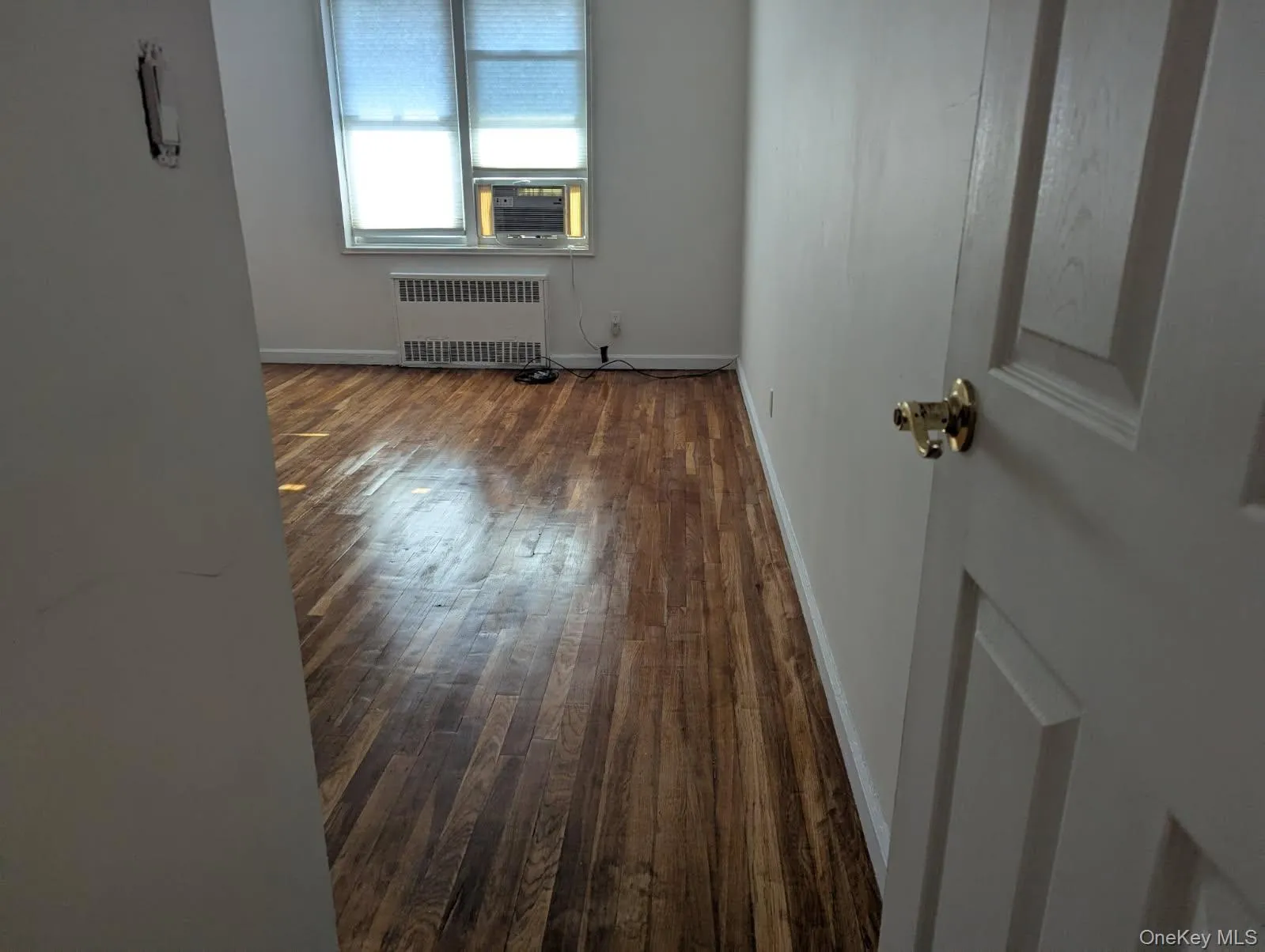 Empty room featuring radiator, dark wood finished floors, and cooling unit Empty room featuring radiator, dark wood finished floors, and cooling unit