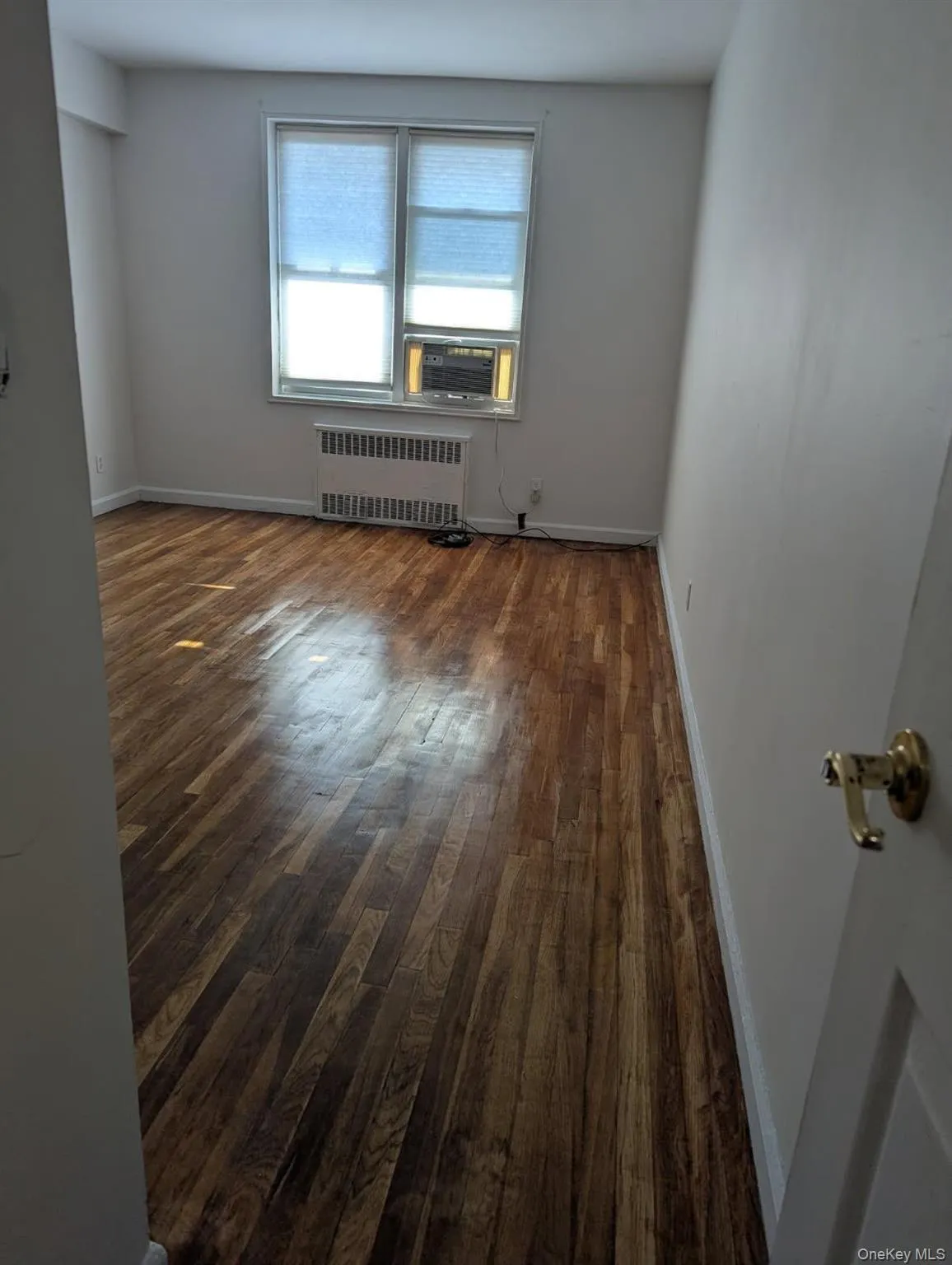 Spare room featuring radiator, dark wood-style flooring, and cooling unit Spare room featuring radiator, dark wood-style flooring, and cooling unit