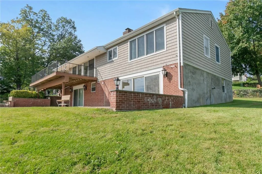 Back of house with a yard, a chimney, and brick siding Back of house with a yard, a chimney, and brick siding