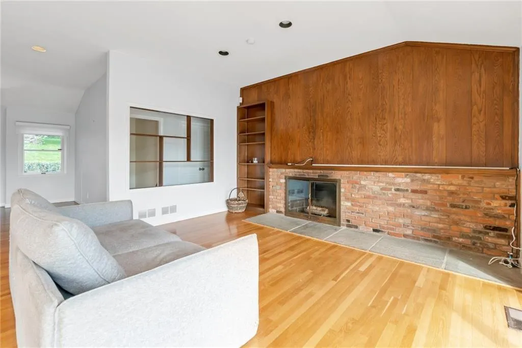 Living area with wood finished floors, a fireplace, and lofted ceiling Living area with wood finished floors, a fireplace, and lofted ceiling