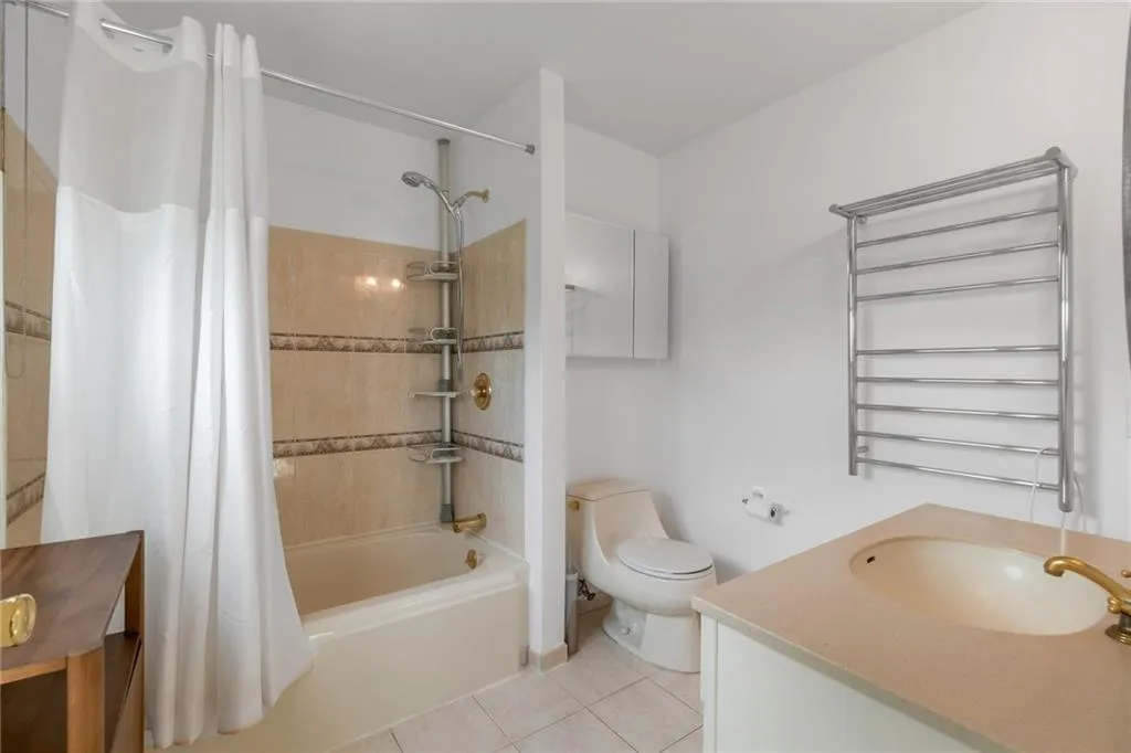 Full bathroom with vanity, toilet, shower / bath combo, and tile patterned floors Full bathroom with vanity, toilet, shower / bath combo, and tile patterned floors