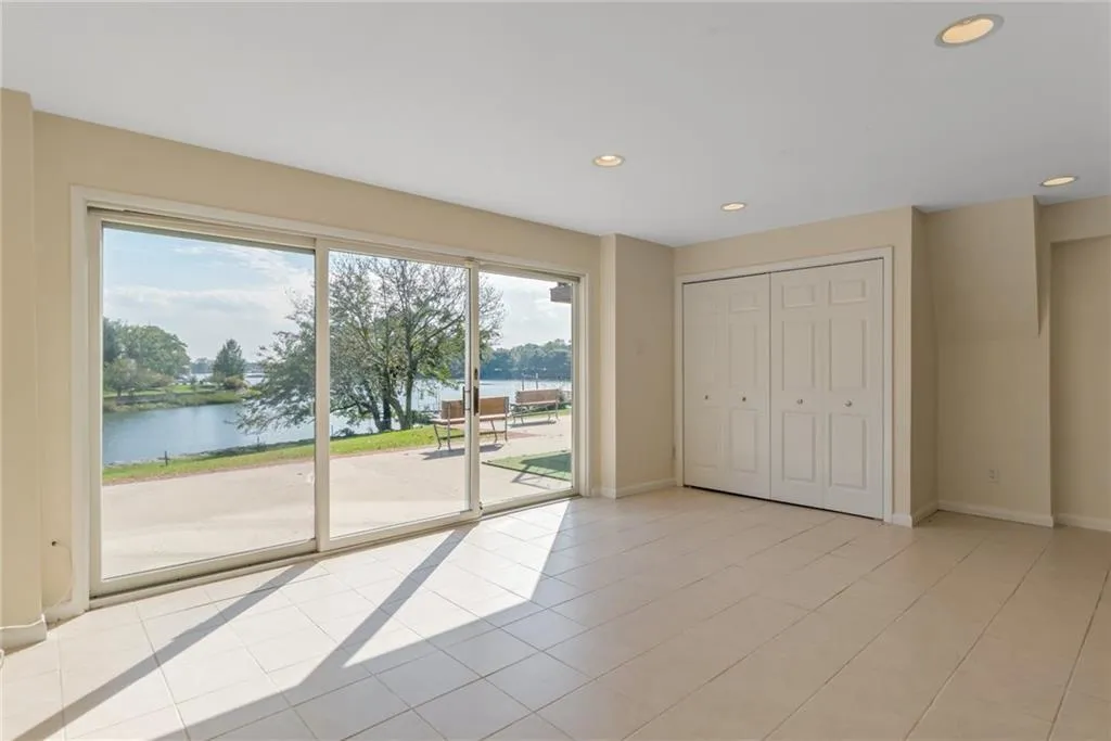 Unfurnished bedroom featuring access to outside, a water view, light tile patterned flooring, recessed lighting, and a closet Unfurnished bedroom featuring access to outside, a water view, light tile patterned flooring, recessed lighting, and a closet
