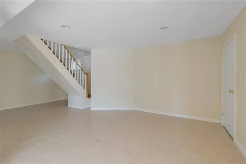 Empty room featuring stairs, baseboards, recessed lighting, and light tile patterned flooring Empty room featuring stairs, baseboards, recessed lighting, and light tile patterned flooring