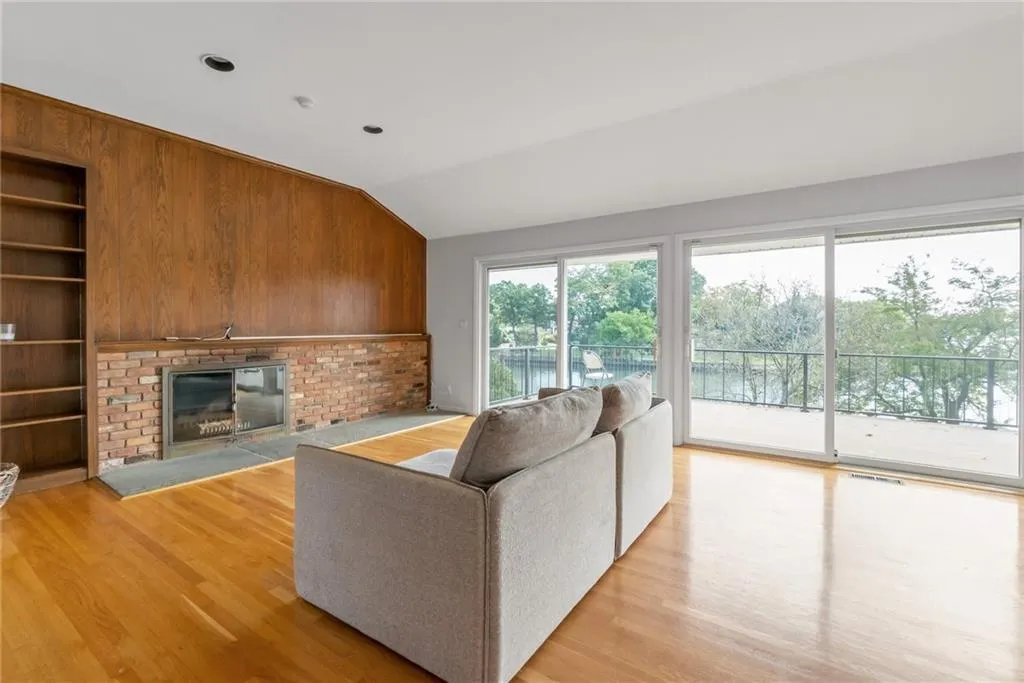 Living area with light wood-type flooring, lofted ceiling, and a brick fireplace Living area with light wood-type flooring, lofted ceiling, and a brick fireplace