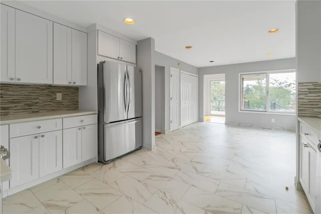 Kitchen featuring freestanding refrigerator, backsplash, light countertops, recessed lighting, and light marble finish floors Kitchen featuring freestanding refrigerator, backsplash, light countertops, recessed lighting, and light marble finish floors