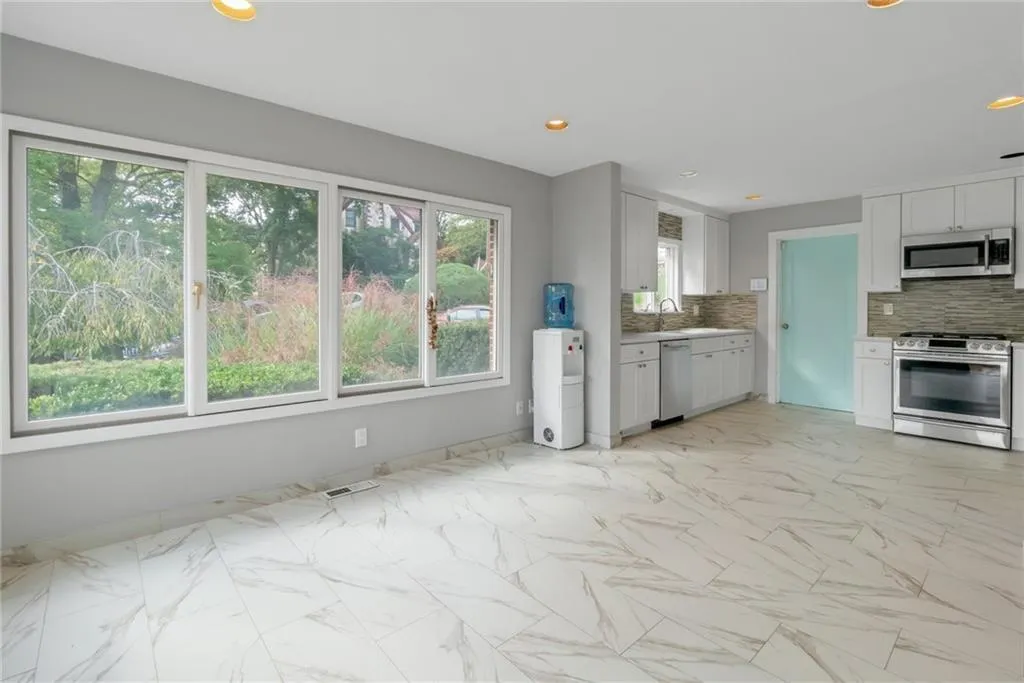 Kitchen with stainless steel appliances, decorative backsplash, light marble finish flooring, baseboards, and light countertops Kitchen with stainless steel appliances, decorative backsplash, light marble finish flooring, baseboards, and light countertops