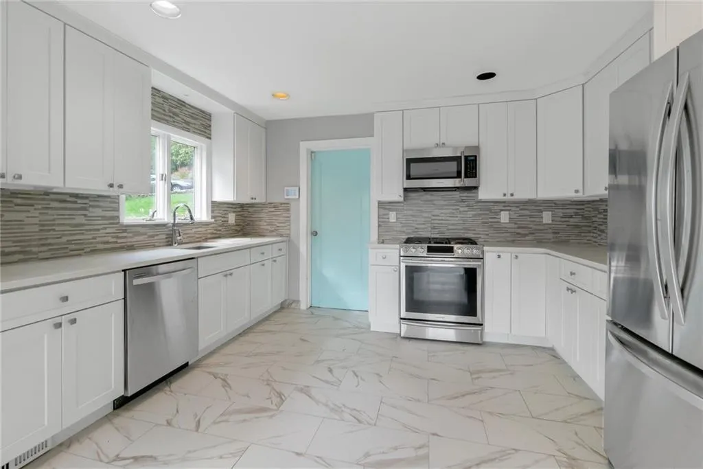 Kitchen featuring stainless steel appliances, light marble finish floors, a sink, light countertops, and recessed lighting Kitchen featuring stainless steel appliances, light marble finish floors, a sink, light countertops, and recessed lighting