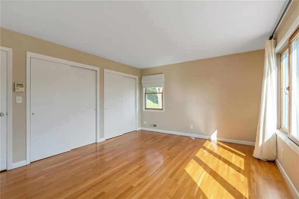 Unfurnished bedroom with light wood-style flooring, multiple closets, and baseboards Unfurnished bedroom with light wood-style flooring, multiple closets, and baseboards
