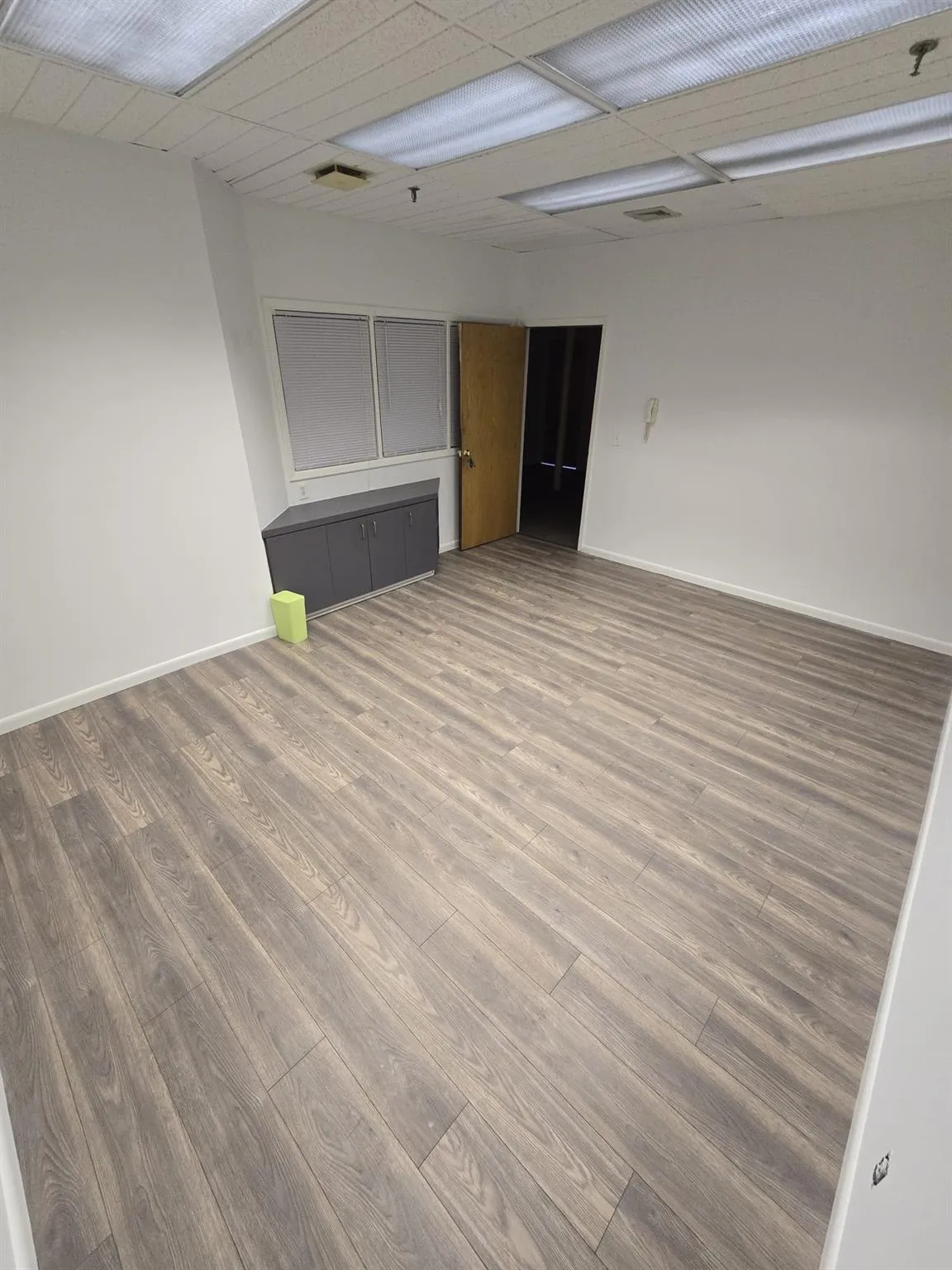 Unfurnished room with wood finished floors, baseboards, and fire sprinkler in ceiling Unfurnished room with wood finished floors, baseboards, and fire sprinkler in ceiling