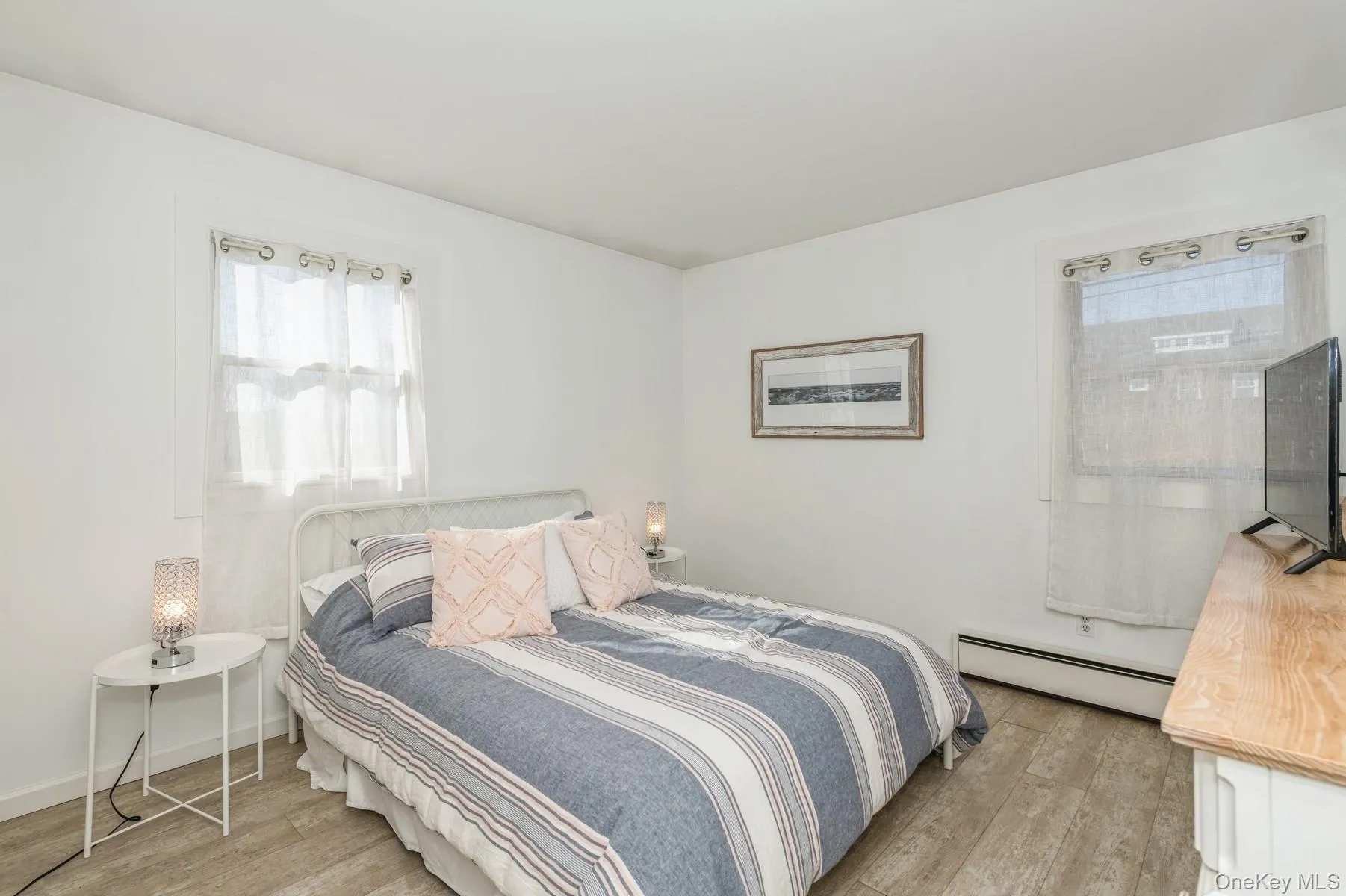 Bedroom with a baseboard heating unit and light wood finished floors Bedroom with a baseboard heating unit and light wood finished floors