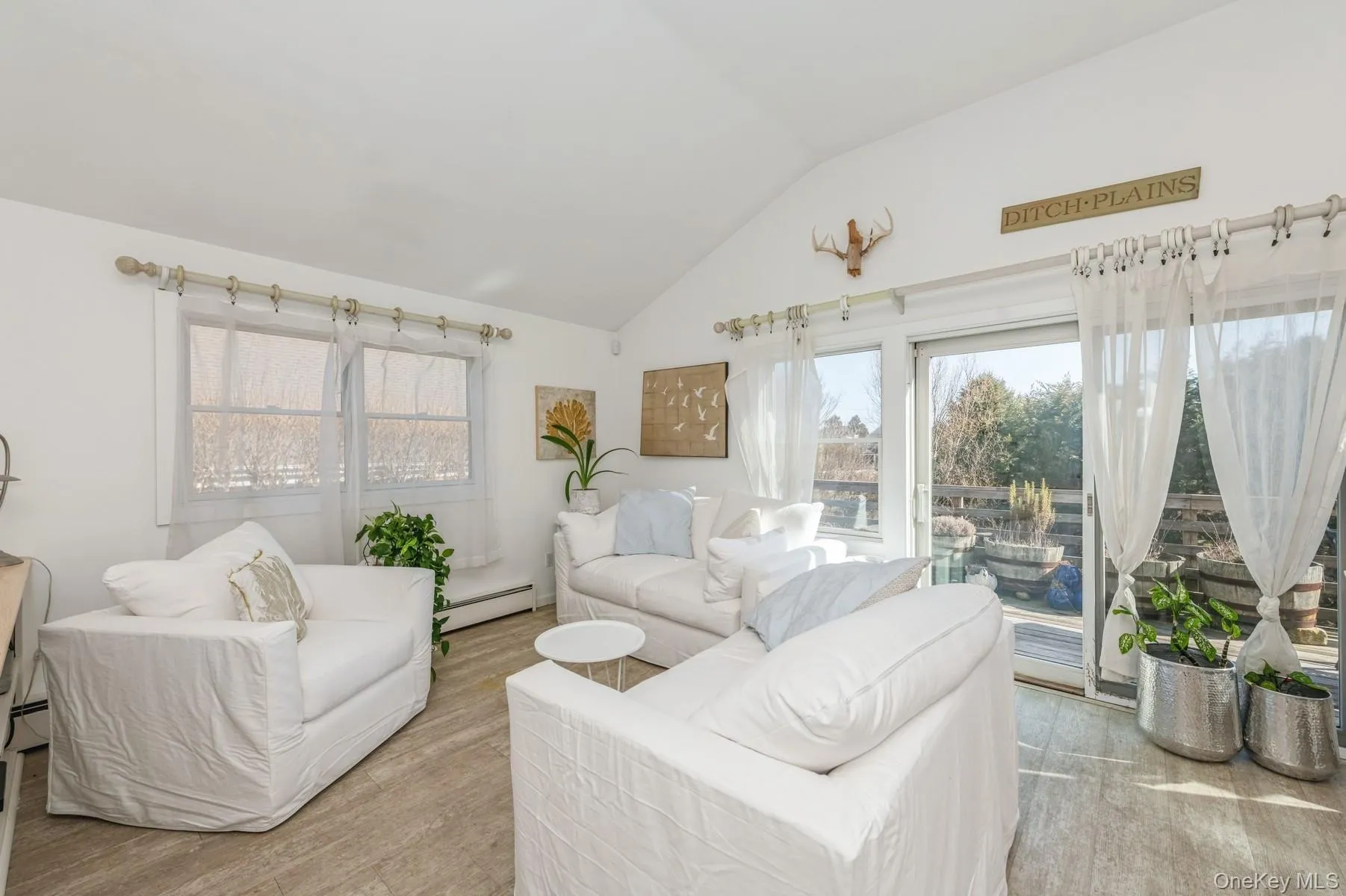 Living room featuring a baseboard heating unit, vaulted ceiling, and light wood-style flooring Living room featuring a baseboard heating unit, vaulted ceiling, and light wood-style flooring