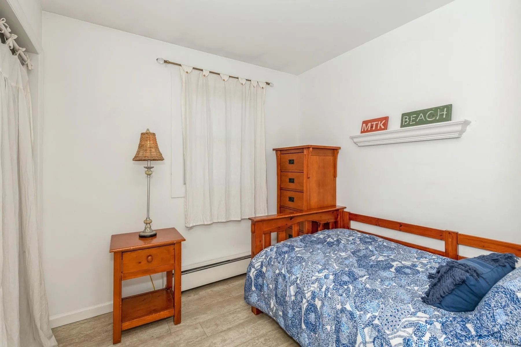 Bedroom featuring a baseboard radiator, wood finished floors, and baseboards Bedroom featuring a baseboard radiator, wood finished floors, and baseboards