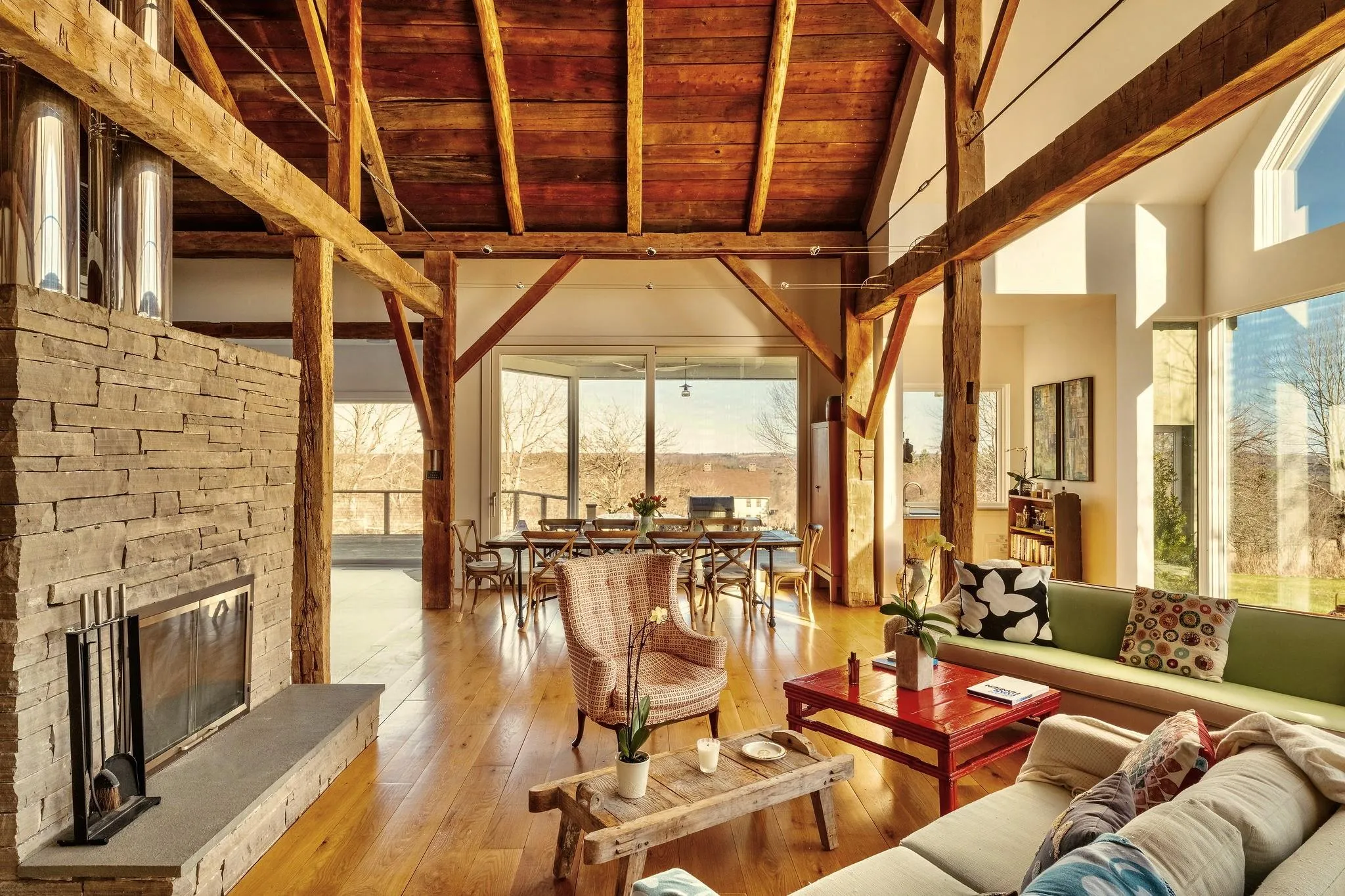 Living area featuring wooden ceiling with exposed beams, a stone fireplace, hardwood / wood-style floors, and high vaulted ceiling Living area featuring wooden ceiling with exposed beams, a stone fireplace, hardwood / wood-style floors, and high vaulted ceiling