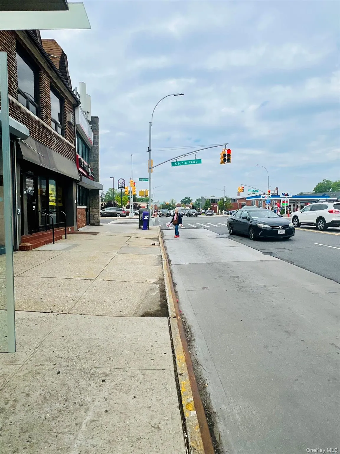 View of asphalt street with curbs, street lighting, traffic lights, and sidewalks View of asphalt street with curbs, street lighting, traffic lights, and sidewalks