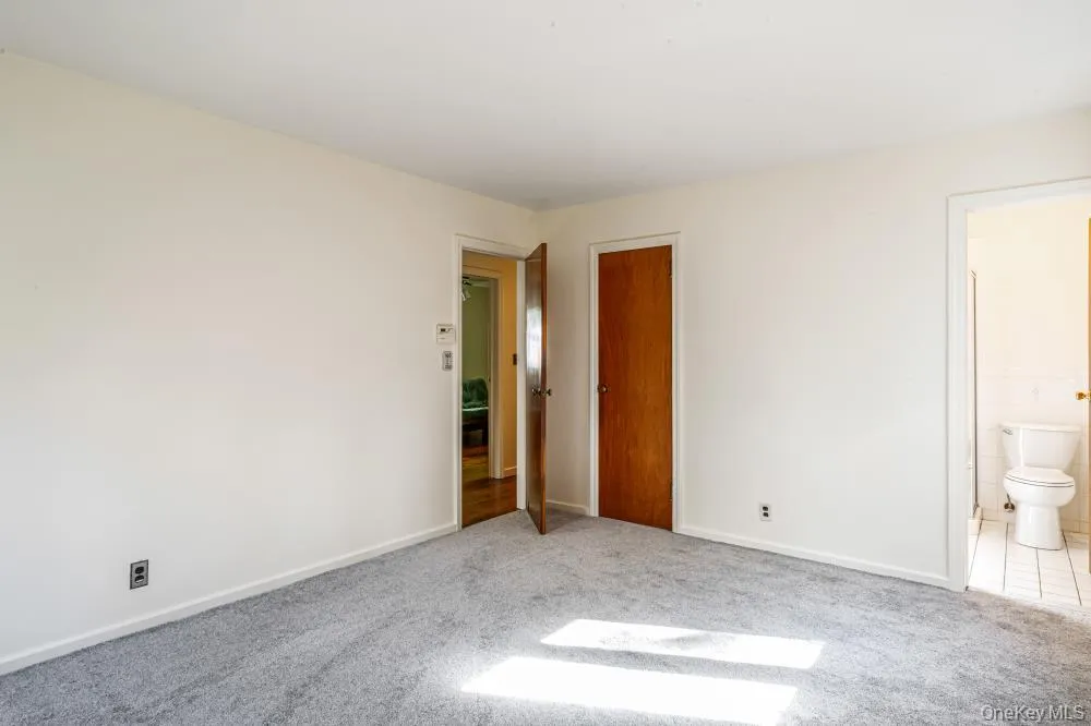Unfurnished bedroom with carpet, a closet, and connected bathroom Unfurnished bedroom with carpet, a closet, and connected bathroom