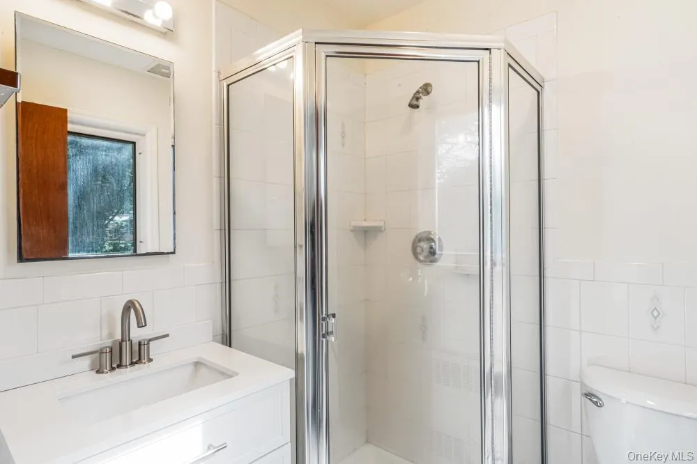 Full bath featuring tile walls, vanity, a shower stall, and backsplash Full bath featuring tile walls, vanity, a shower stall, and backsplash