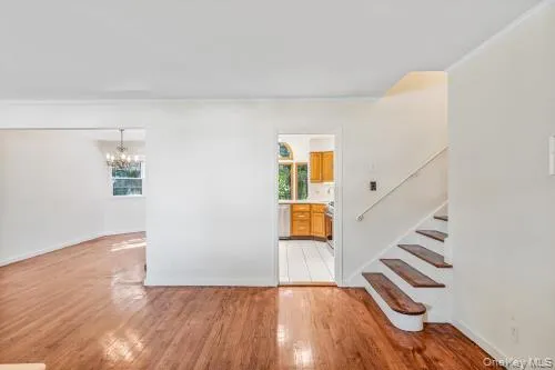 Unfurnished room featuring light wood finished floors, a chandelier, and stairway Unfurnished room featuring light wood finished floors, a chandelier, and stairway