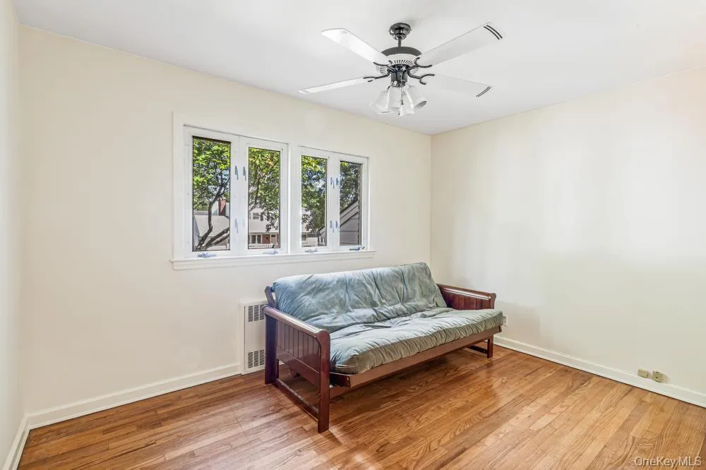 Sitting room featuring light wood finished floors, radiator heating unit, and a ceiling fan Sitting room featuring light wood finished floors, radiator heating unit, and a ceiling fan