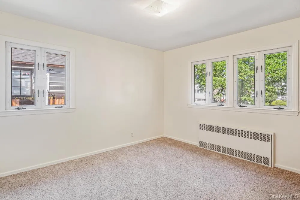 Empty room featuring radiator and carpet flooring Empty room featuring radiator and carpet flooring