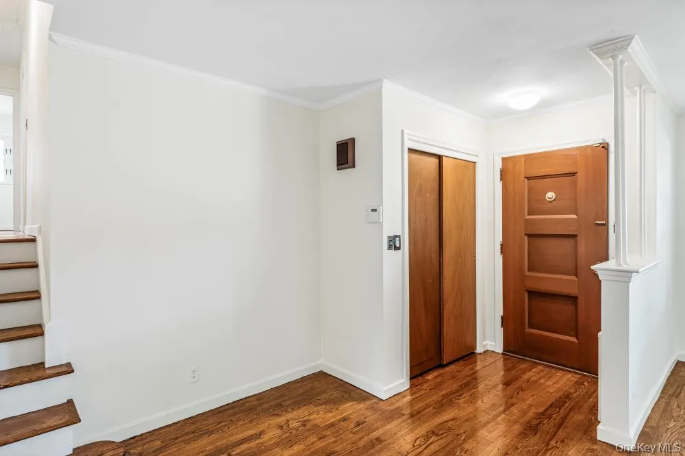 Foyer featuring ornamental molding, dark wood-style floors, and stairs Foyer featuring ornamental molding, dark wood-style floors, and stairs