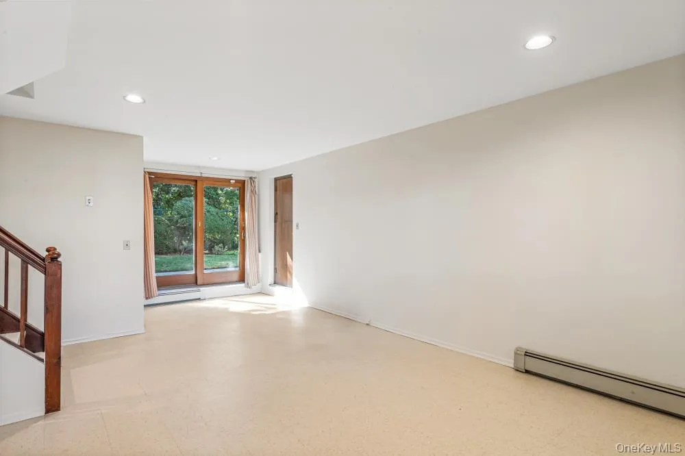 Empty room with light flooring, recessed lighting, stairway, a baseboard heating unit, and baseboard heating Empty room with light flooring, recessed lighting, stairway, a baseboard heating unit, and baseboard heating