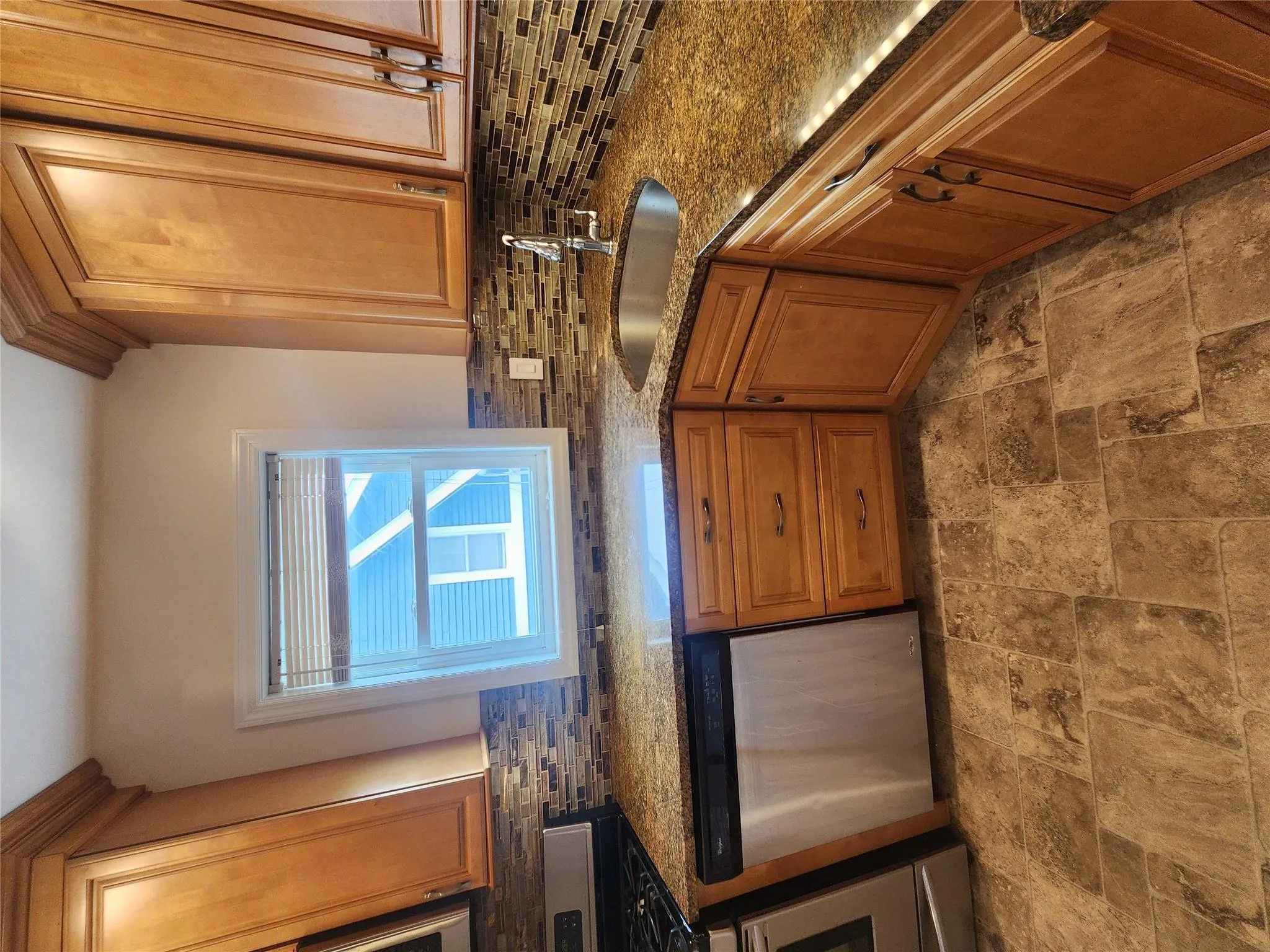 Kitchen featuring dishwasher, stove, decorative backsplash, stone finish floors, and dark stone counters Kitchen featuring dishwasher, stove, decorative backsplash, stone finish floors, and dark stone counters