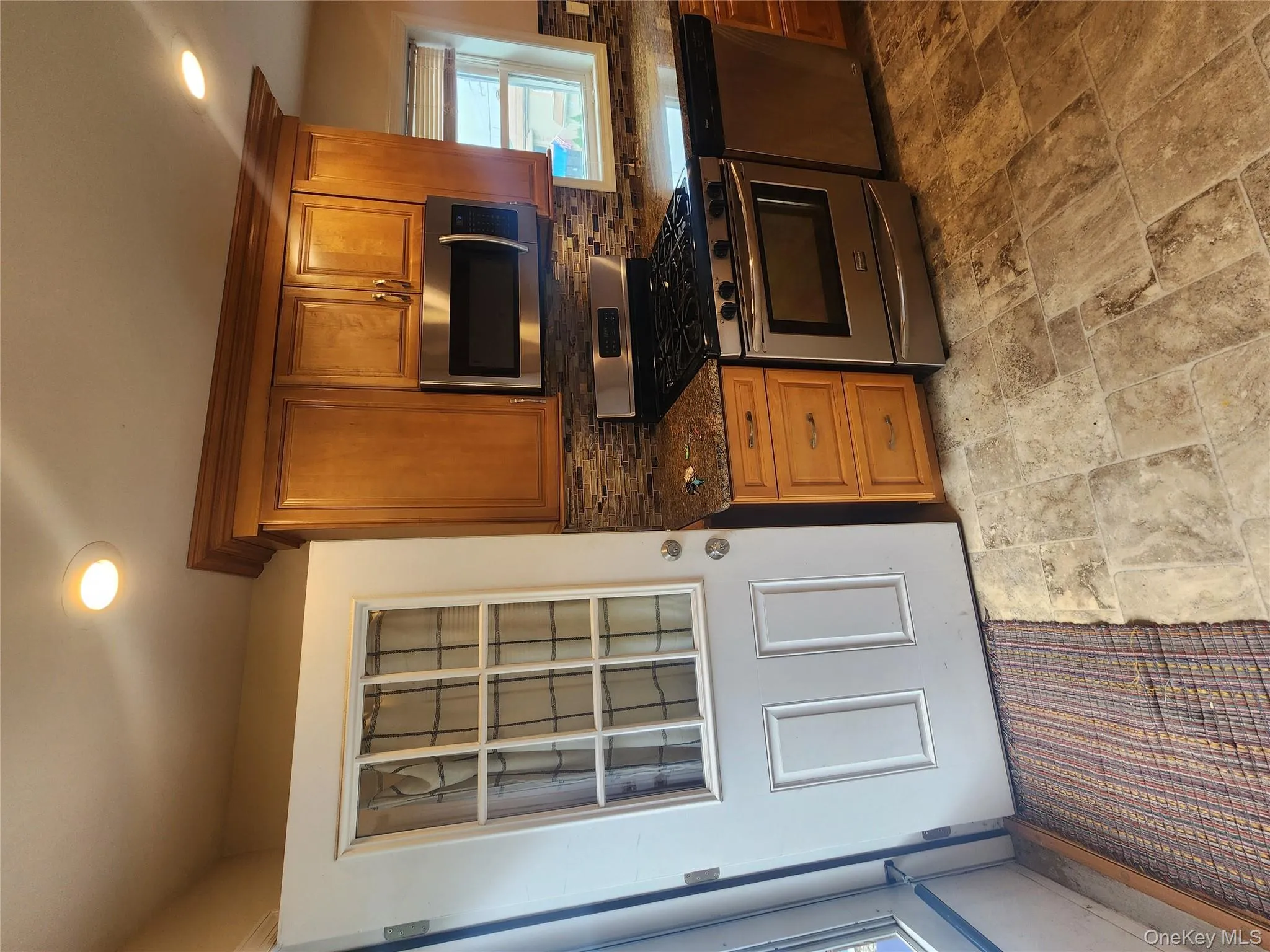 Kitchen featuring range, dishwashing machine, decorative backsplash, brown cabinets, and light stone finish floors Kitchen featuring range, dishwashing machine, decorative backsplash, brown cabinets, and light stone finish floors