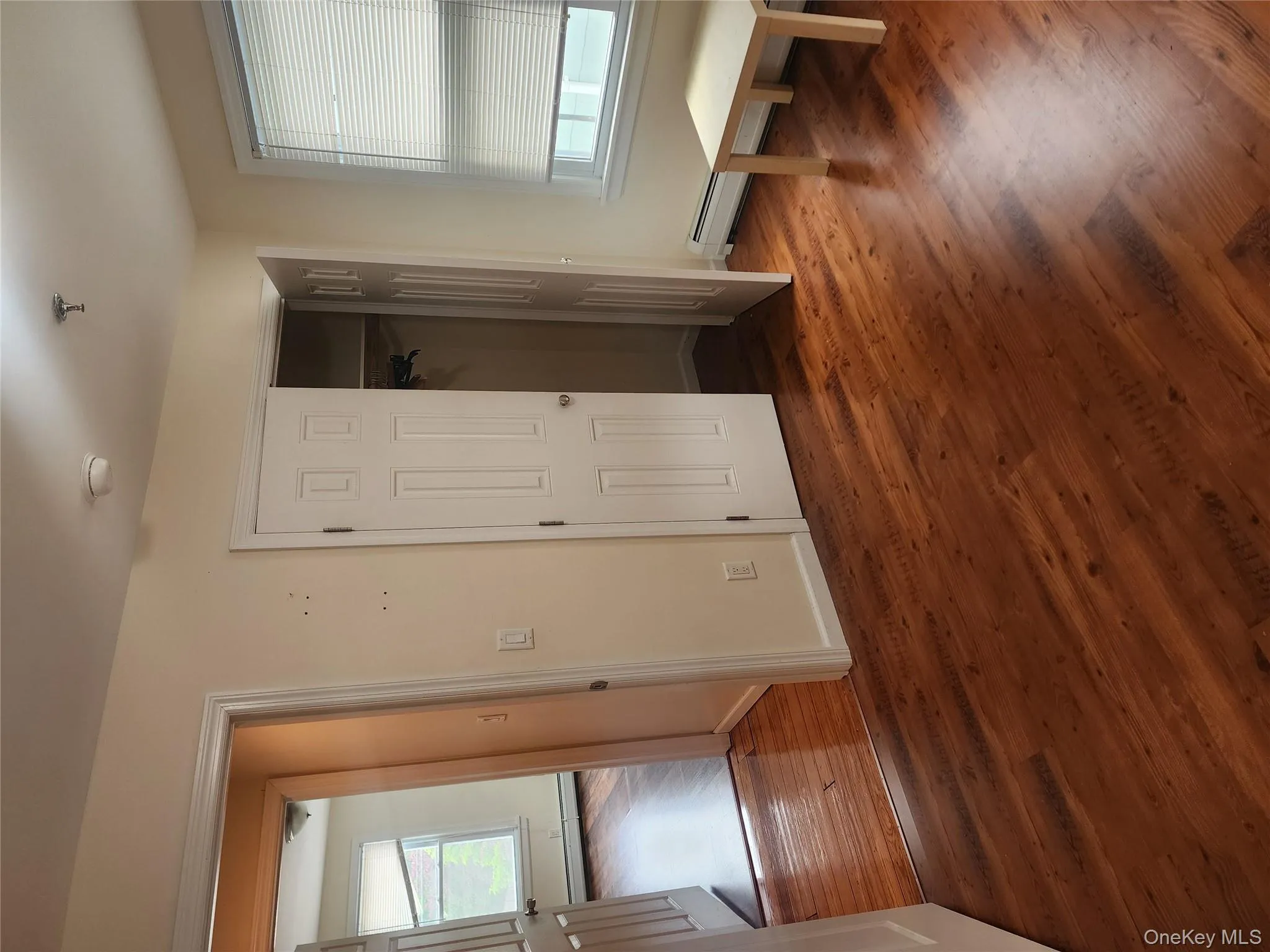 Unfurnished bedroom with baseboard heating, dark wood-type flooring, and a closet Unfurnished bedroom with baseboard heating, dark wood-type flooring, and a closet