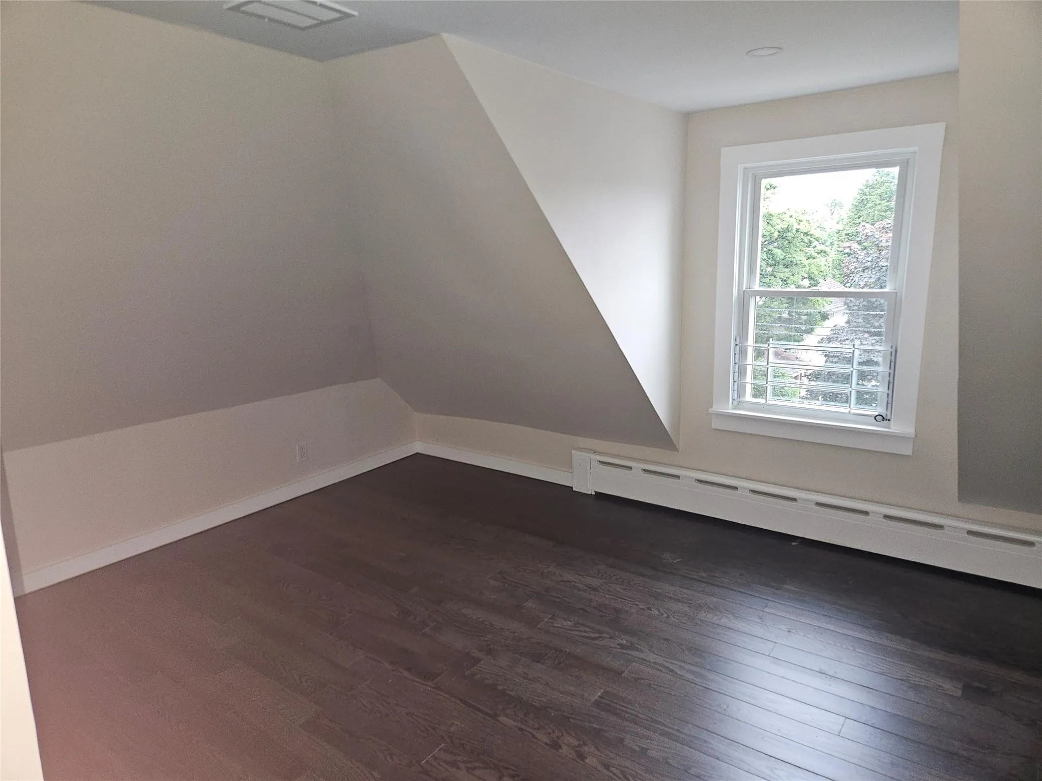 Bonus room featuring a baseboard heating unit and dark wood-style flooring Bonus room featuring a baseboard heating unit and dark wood-style flooring