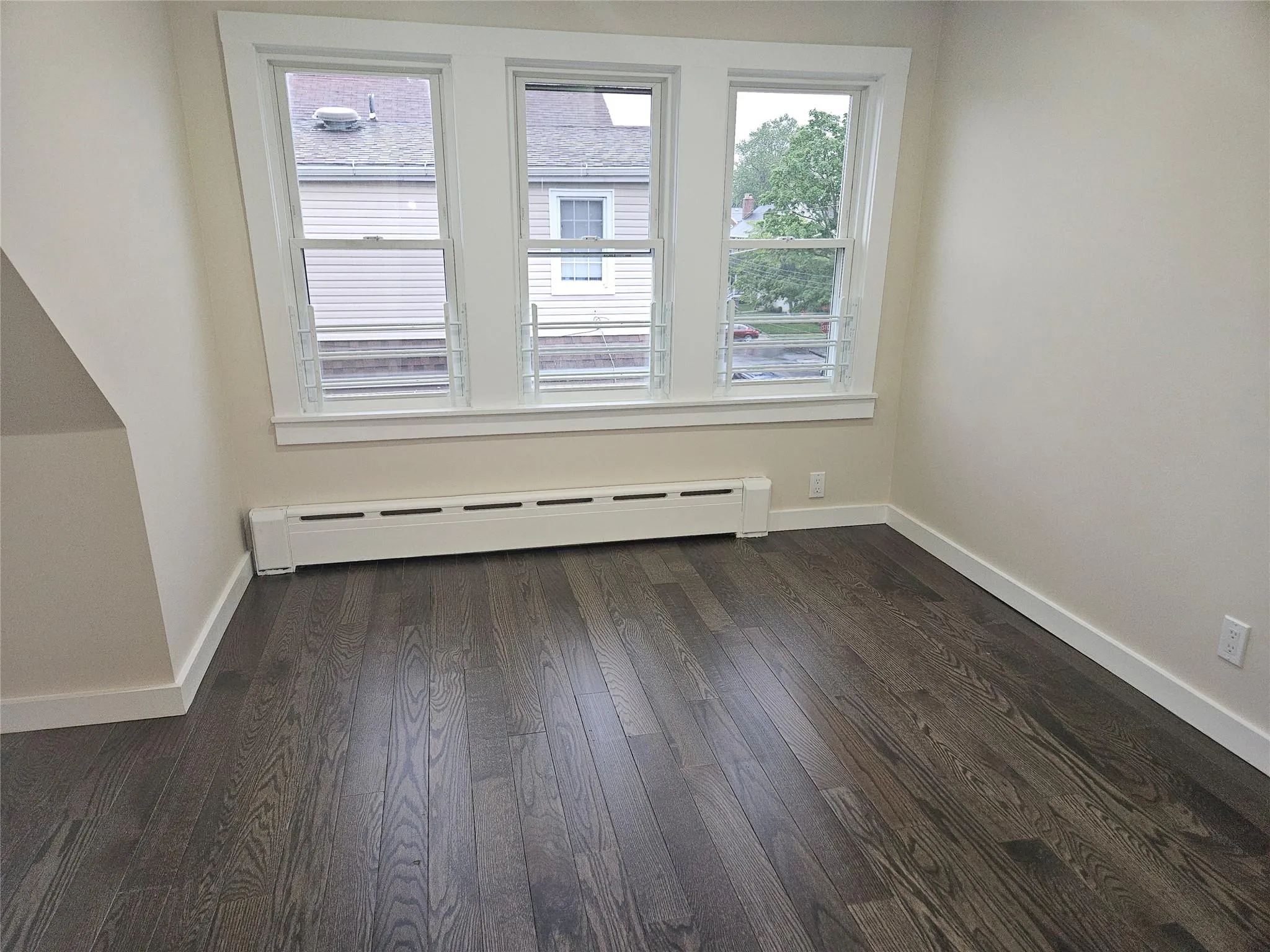 Spare room with baseboard heating, dark wood finished floors, and baseboards Spare room with baseboard heating, dark wood finished floors, and baseboards