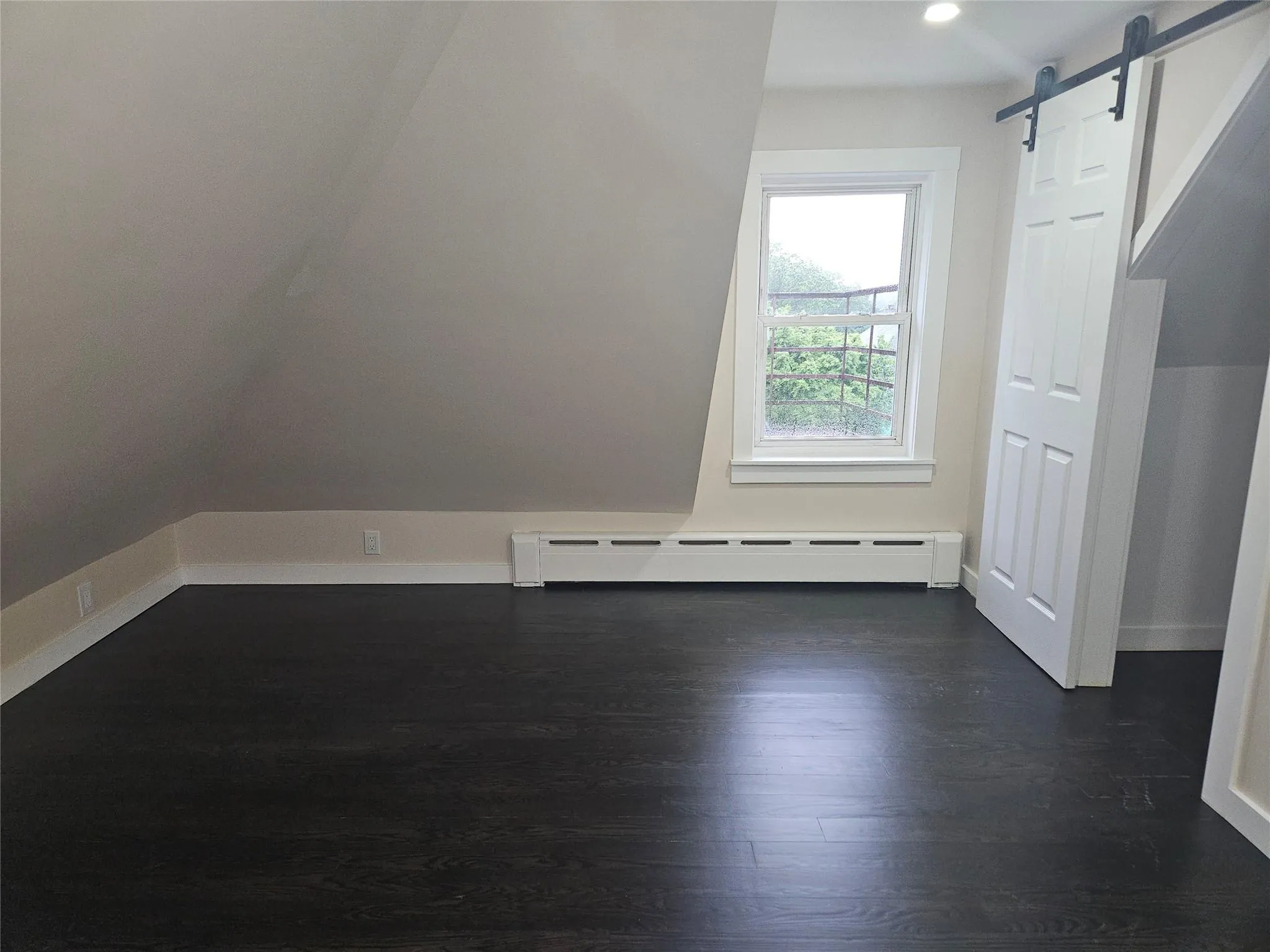 Additional living space featuring a baseboard heating unit, dark wood-style flooring, a barn door, baseboards, and recessed lighting Additional living space featuring a baseboard heating unit, dark wood-style flooring, a barn door, baseboards, and recessed lighting