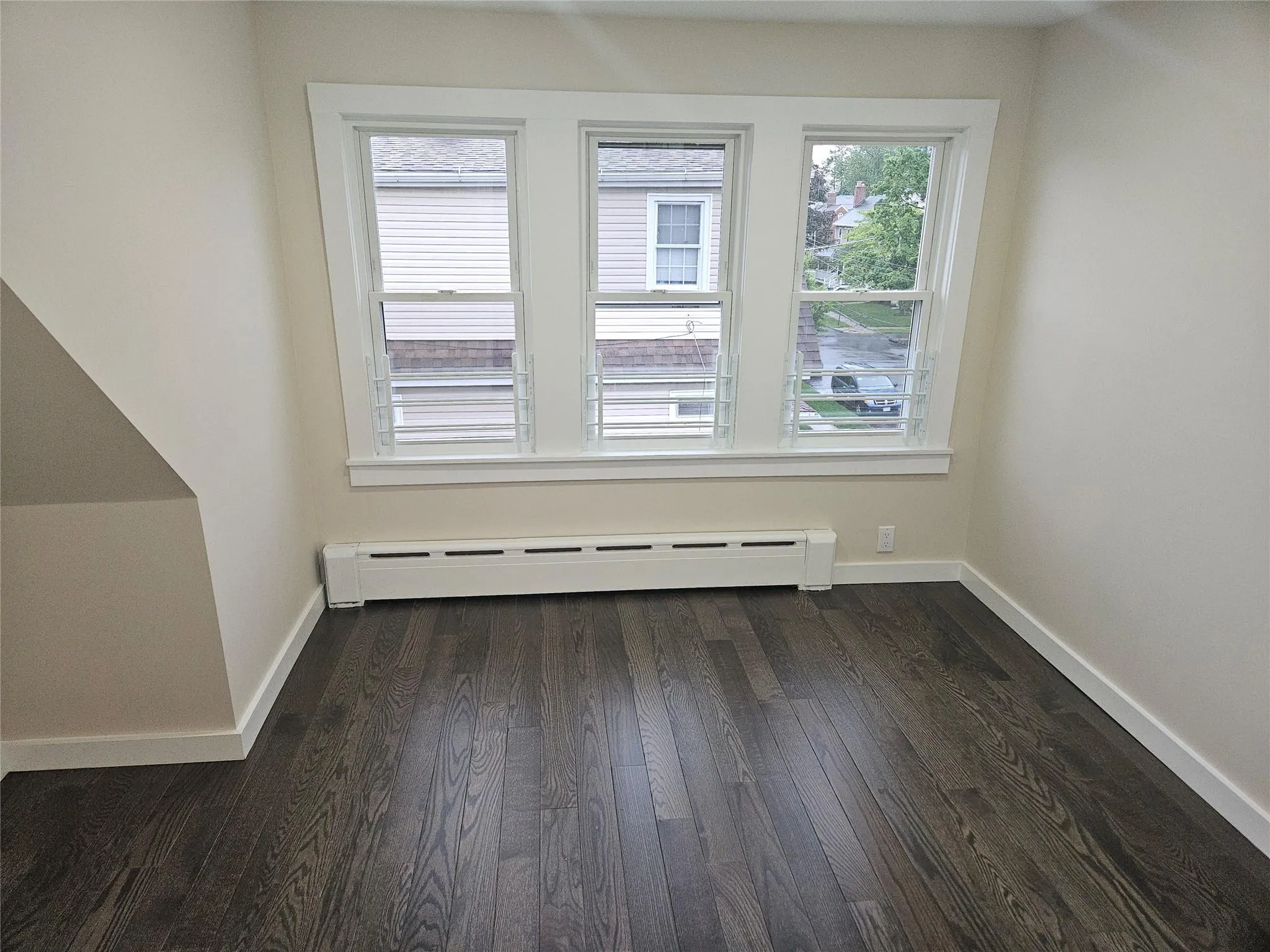 Bonus room featuring a baseboard radiator, dark wood-style floors, and baseboards Bonus room featuring a baseboard radiator, dark wood-style floors, and baseboards