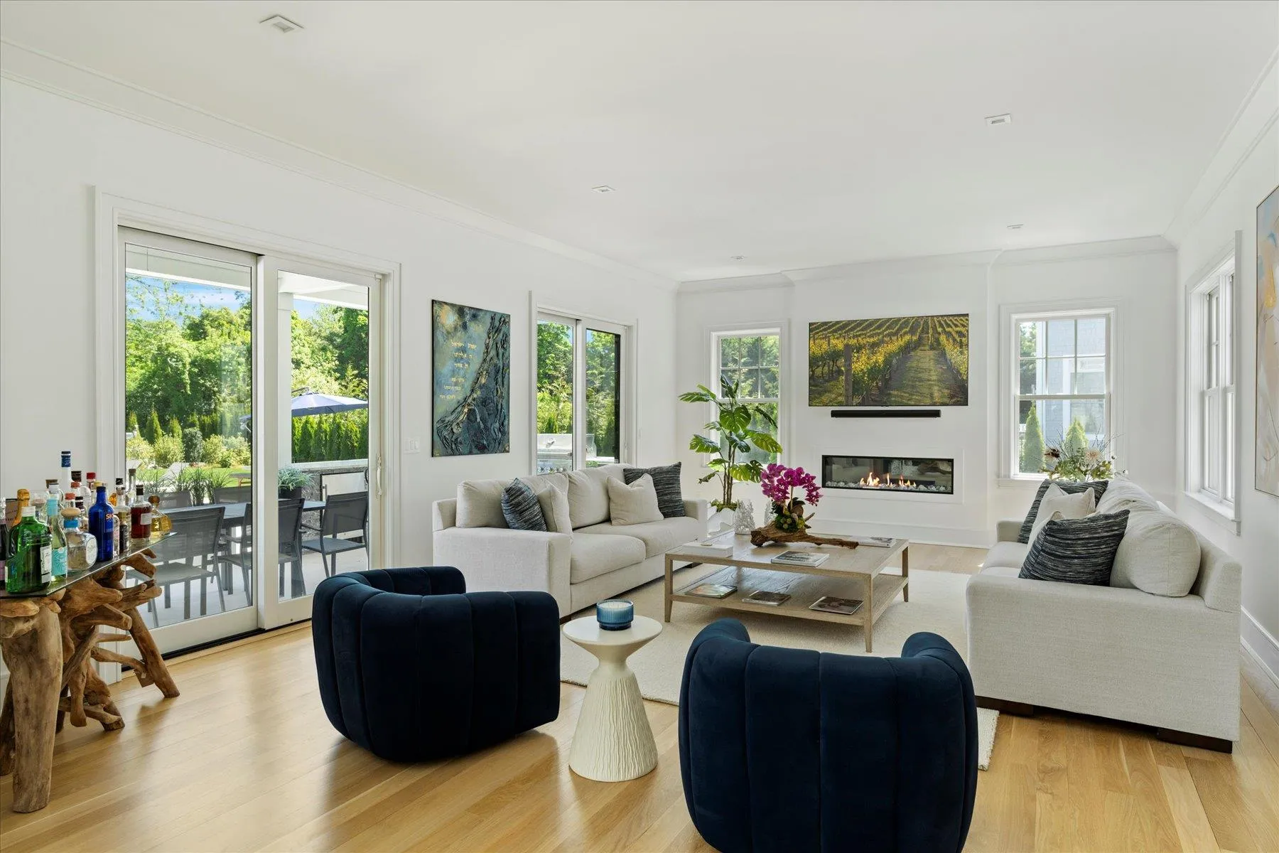 Living room with crown molding, a glass covered fireplace, and light wood-style flooring Living room with crown molding, a glass covered fireplace, and light wood-style flooring