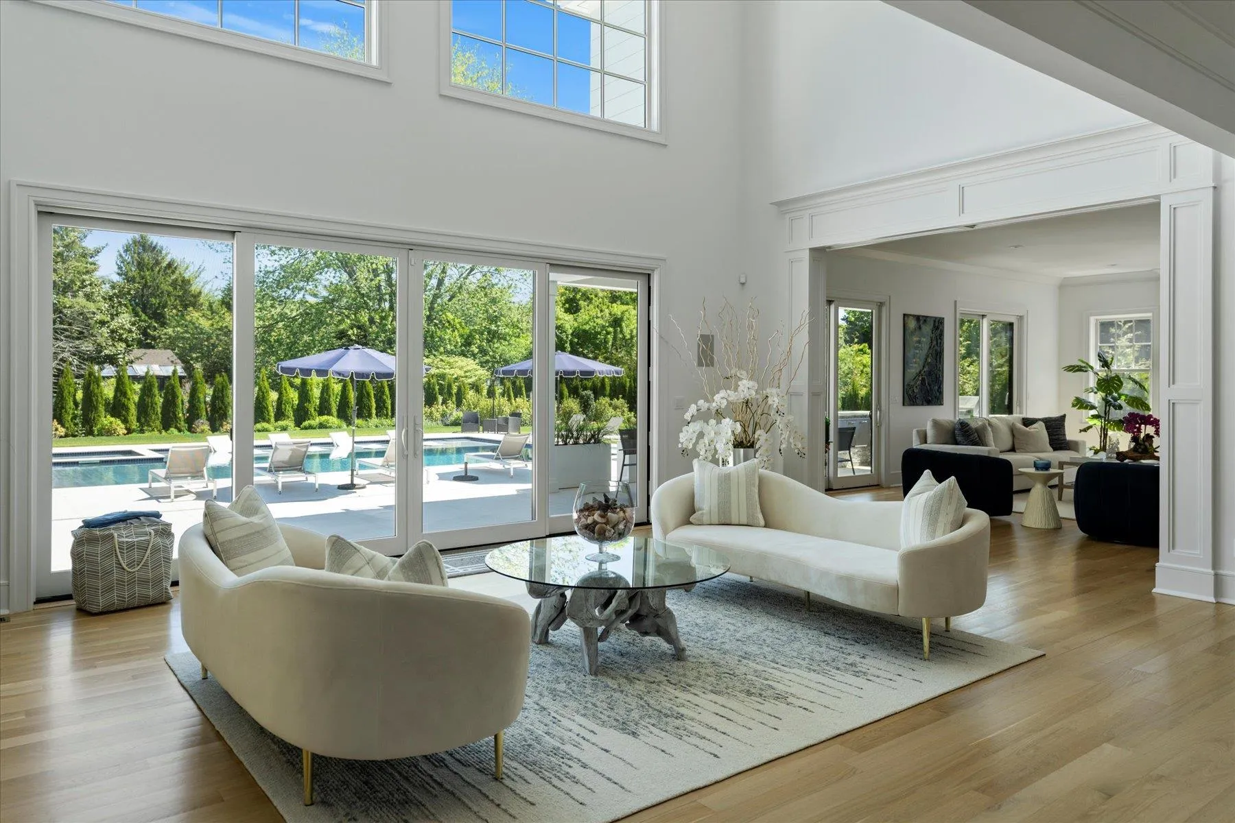 Living area featuring healthy amount of natural light, a high ceiling, and light wood-style floors Living area featuring healthy amount of natural light, a high ceiling, and light wood-style floors