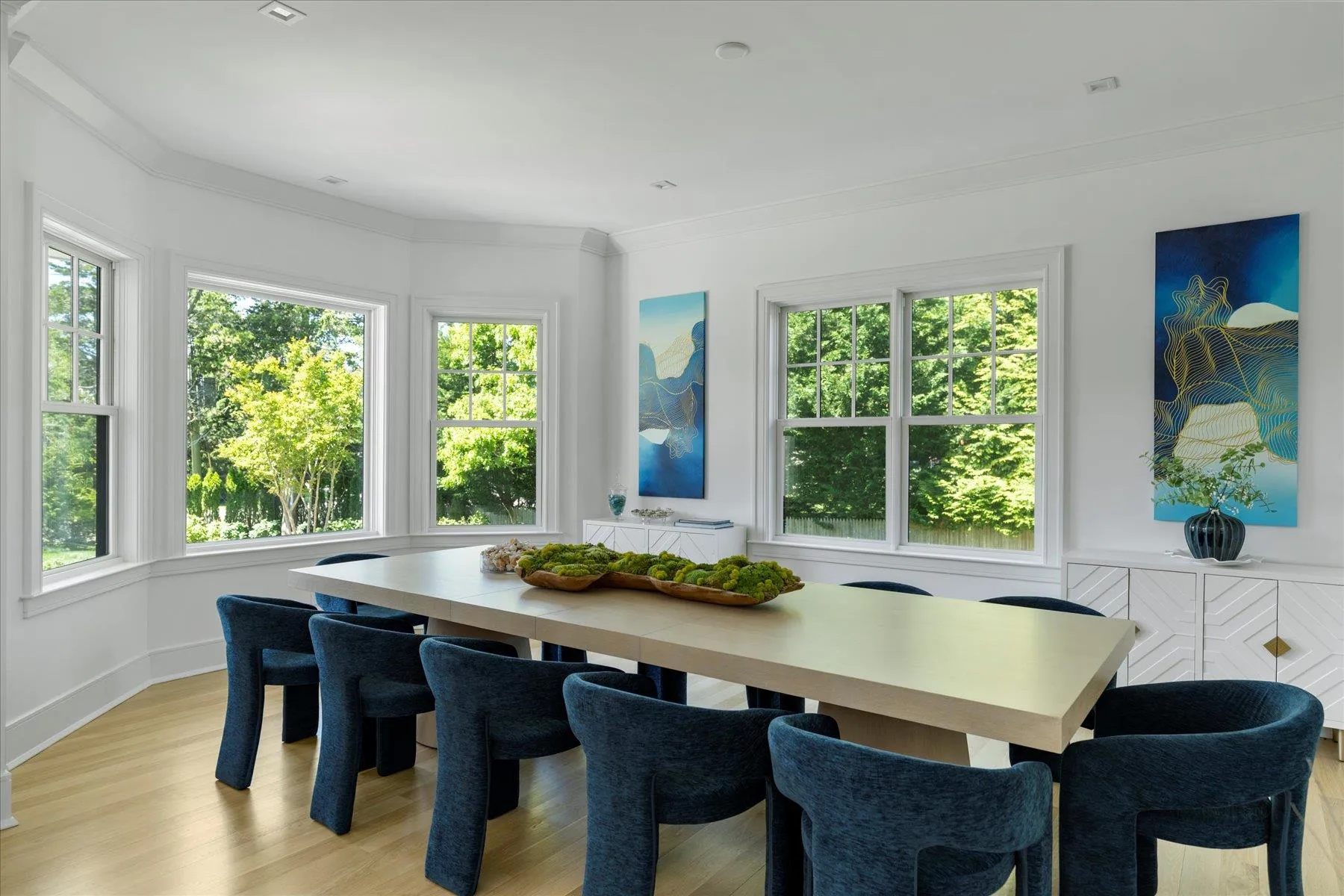 Dining space with healthy amount of natural light, light wood-style flooring, crown molding, and baseboards Dining space with healthy amount of natural light, light wood-style flooring, crown molding, and baseboards