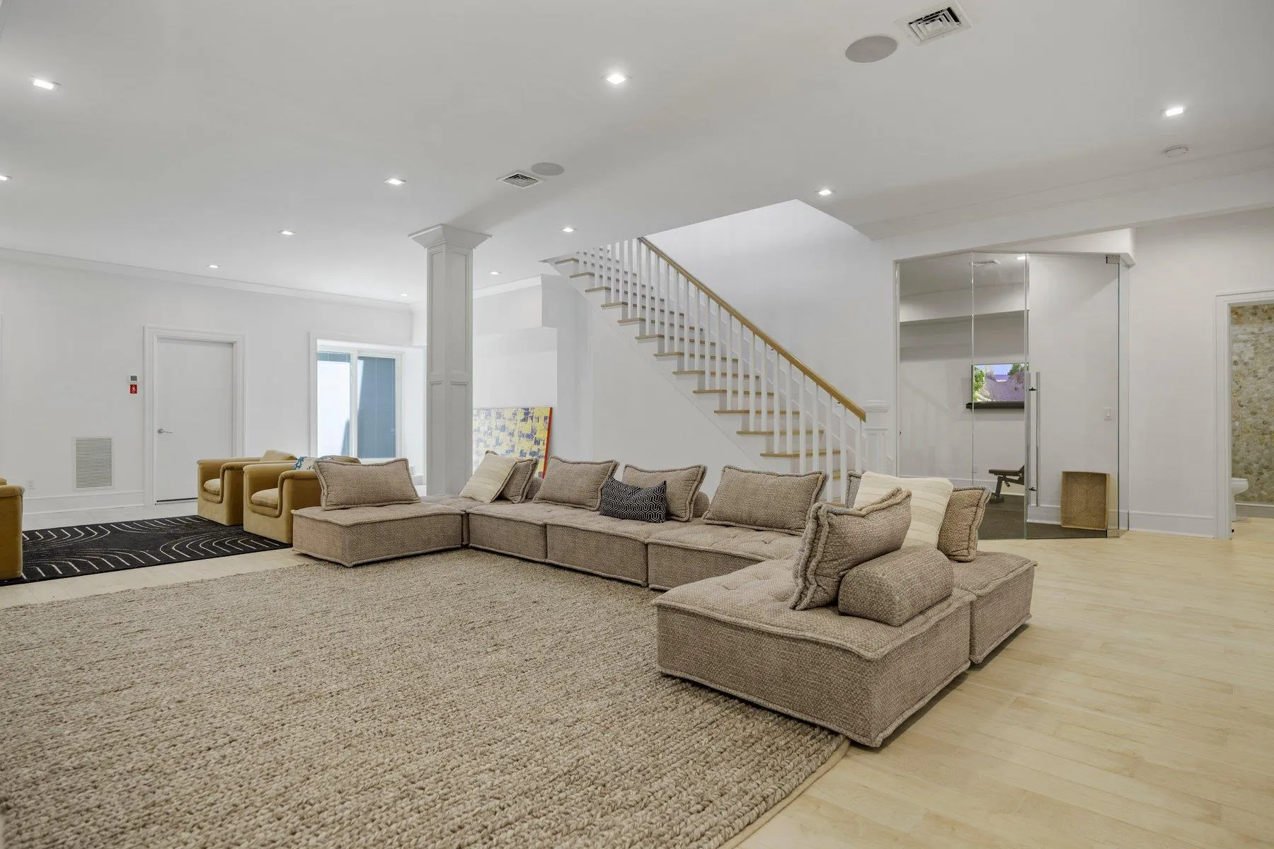 Living room with light wood finished floors, recessed lighting, stairway, decorative columns, and baseboards Living room with light wood finished floors, recessed lighting, stairway, decorative columns, and baseboards