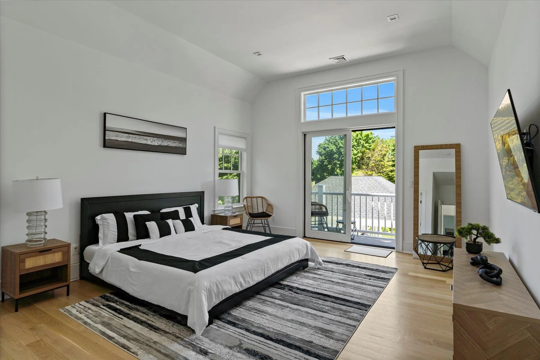 Bedroom featuring vaulted ceiling, access to exterior, and wood finished floors Bedroom featuring vaulted ceiling, access to exterior, and wood finished floors