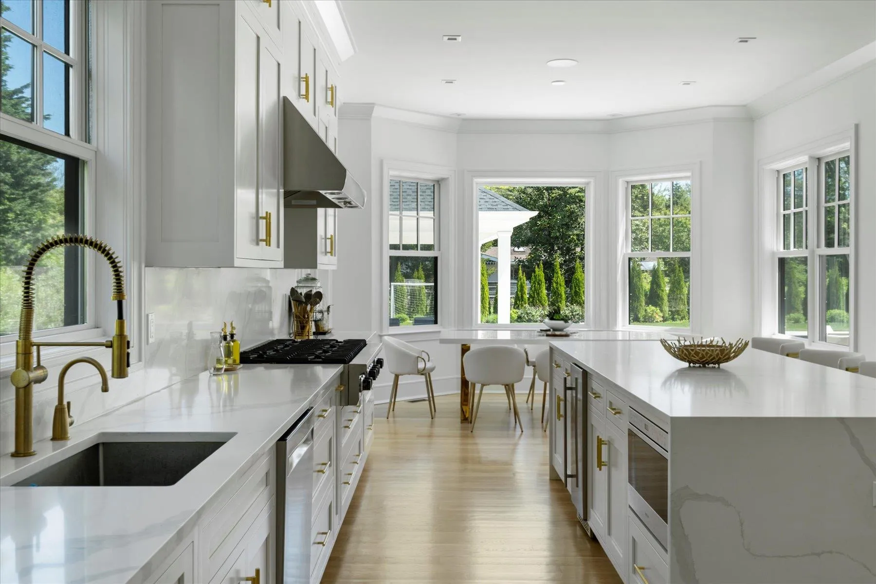 Kitchen featuring a sink, gas stovetop, wood finished floors, light stone counters, and white cabinets Kitchen featuring a sink, gas stovetop, wood finished floors, light stone counters, and white cabinets